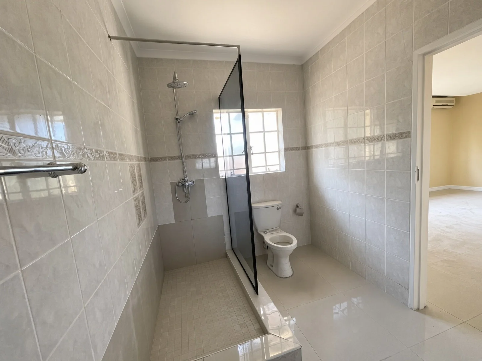 Ensuite with walk-in shower, toilet and window in a 5-bedroom rental in Block 9 Gaborone