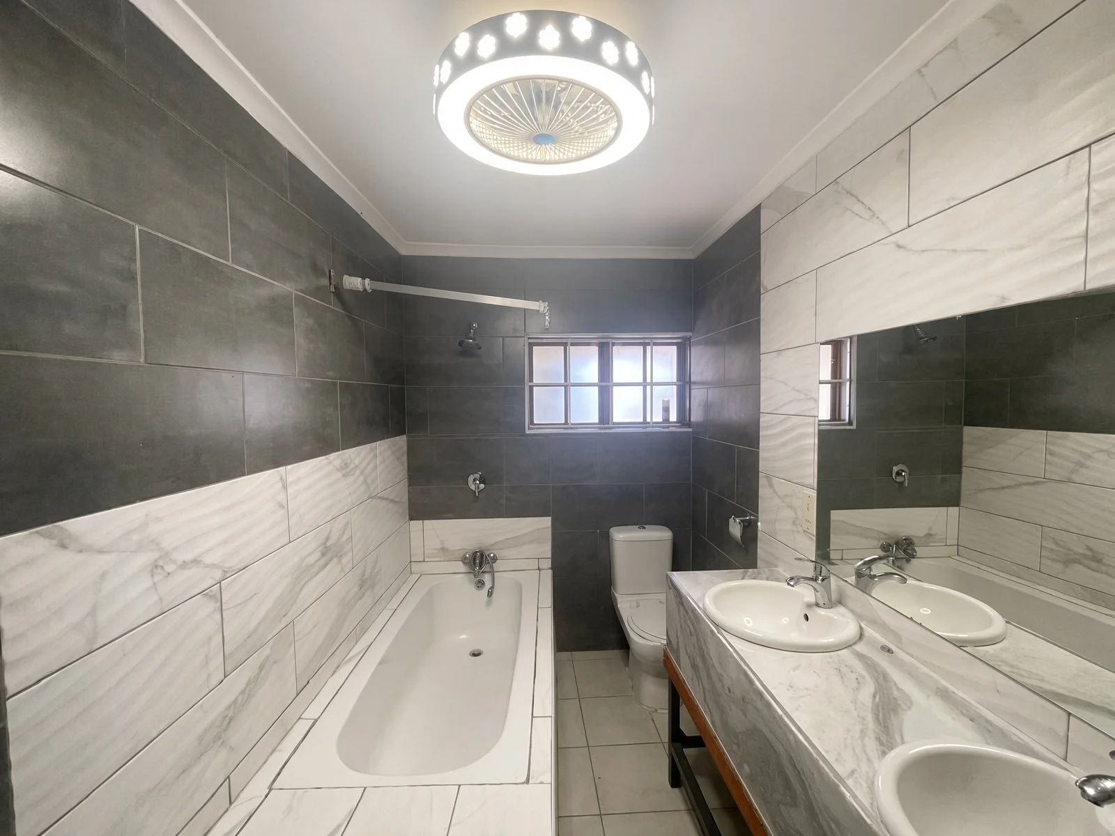Ensuite bathroom with bathtub, double marble vanity and toilet in a 4-bedroom Phakalane rental