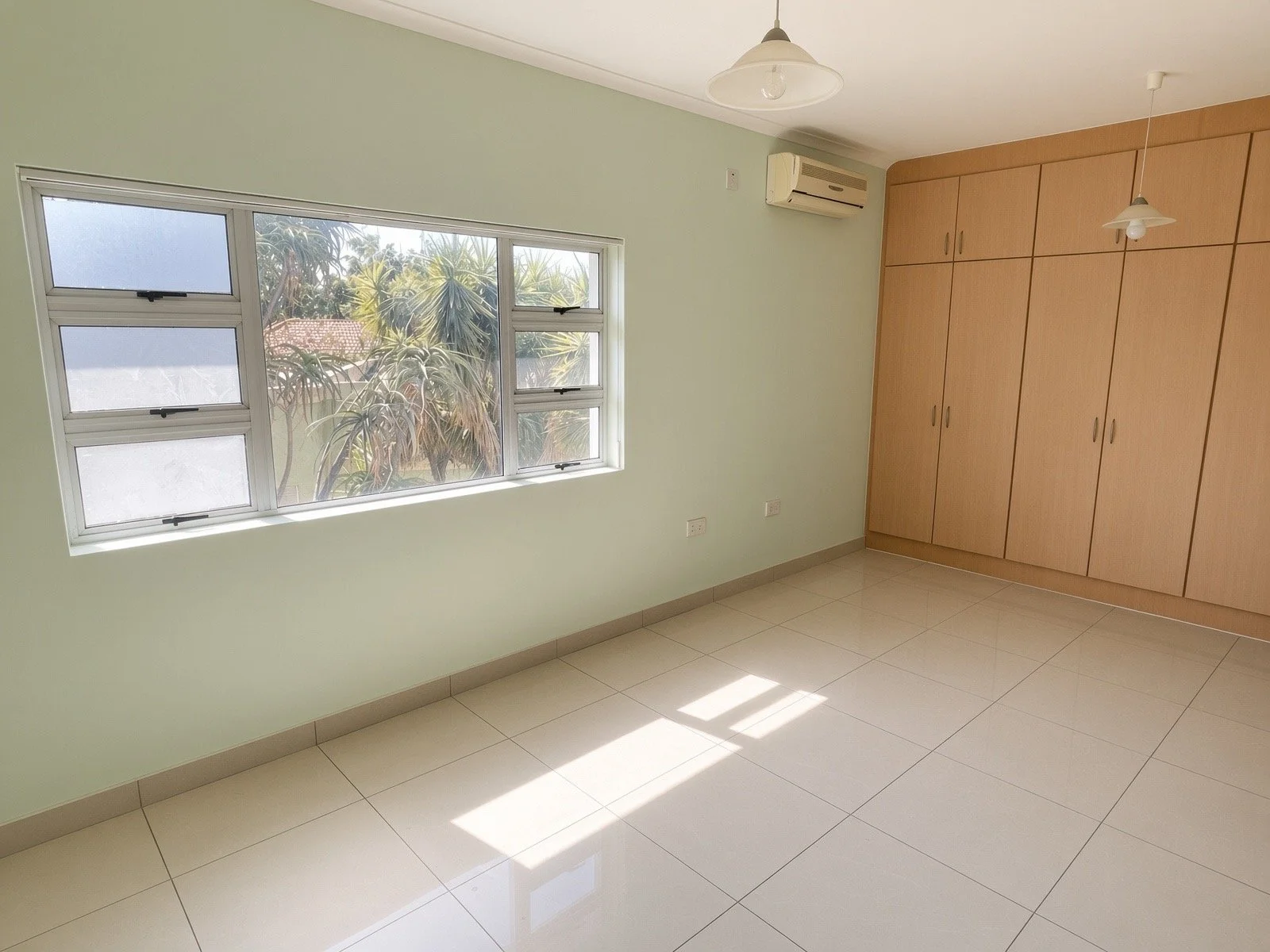 Air-conditioned bedroom with fitted wooden wardrobes, mint walls and garden views in a 4-bedroom house for rent in a gated estate, Phakalane. Nestgeeks.