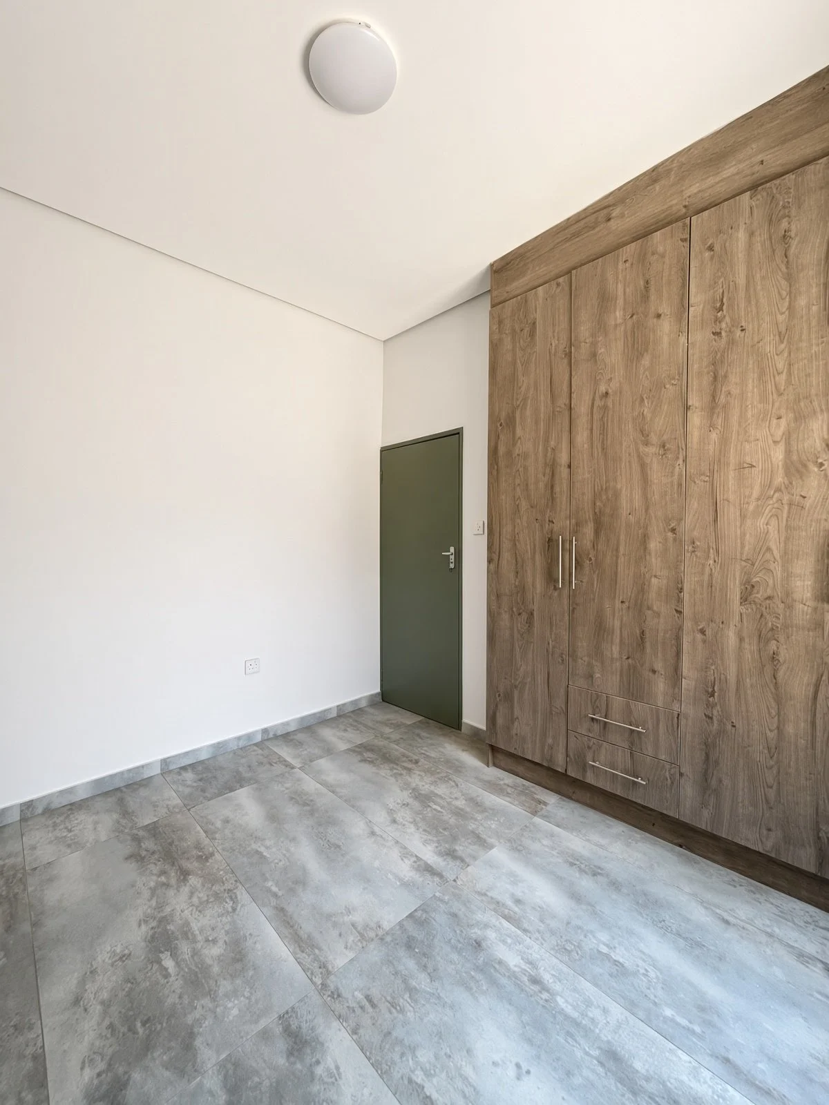 Bedroom with wood-grain built-in cupboards and green door in a 2-bedroom Maruapula rental