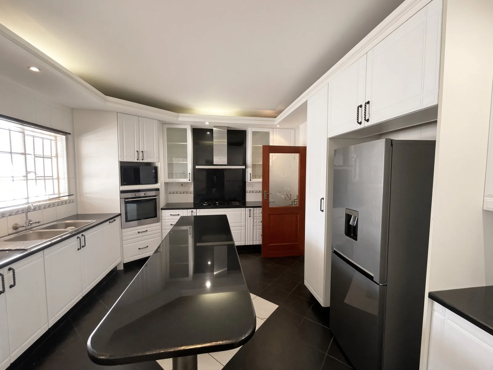 Modern fitted kitchen with fridge, granite island and ample storage in the spacious 5-bedroom furnished rental, Phakalane. Nestgeeks listing.