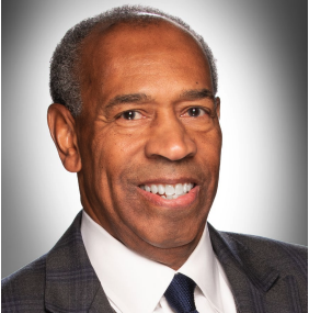 Professional headshot Jim Mason in a dark suit, white shirt, and navy tie with a neutral gray background.