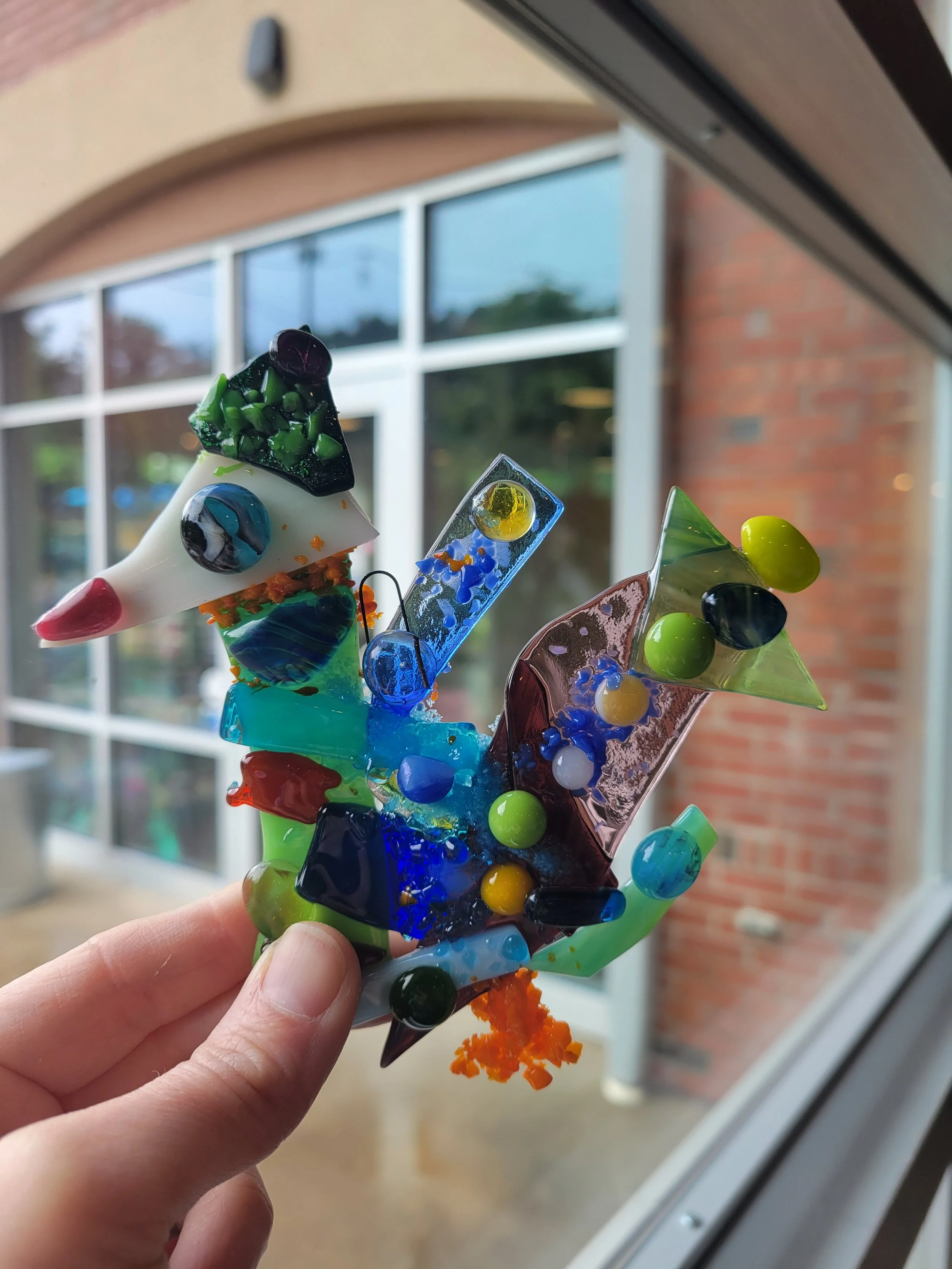 Pictured is a fused glass "freeform" creation built from small pieces of glass and beads in the shape of a dodo bird.
