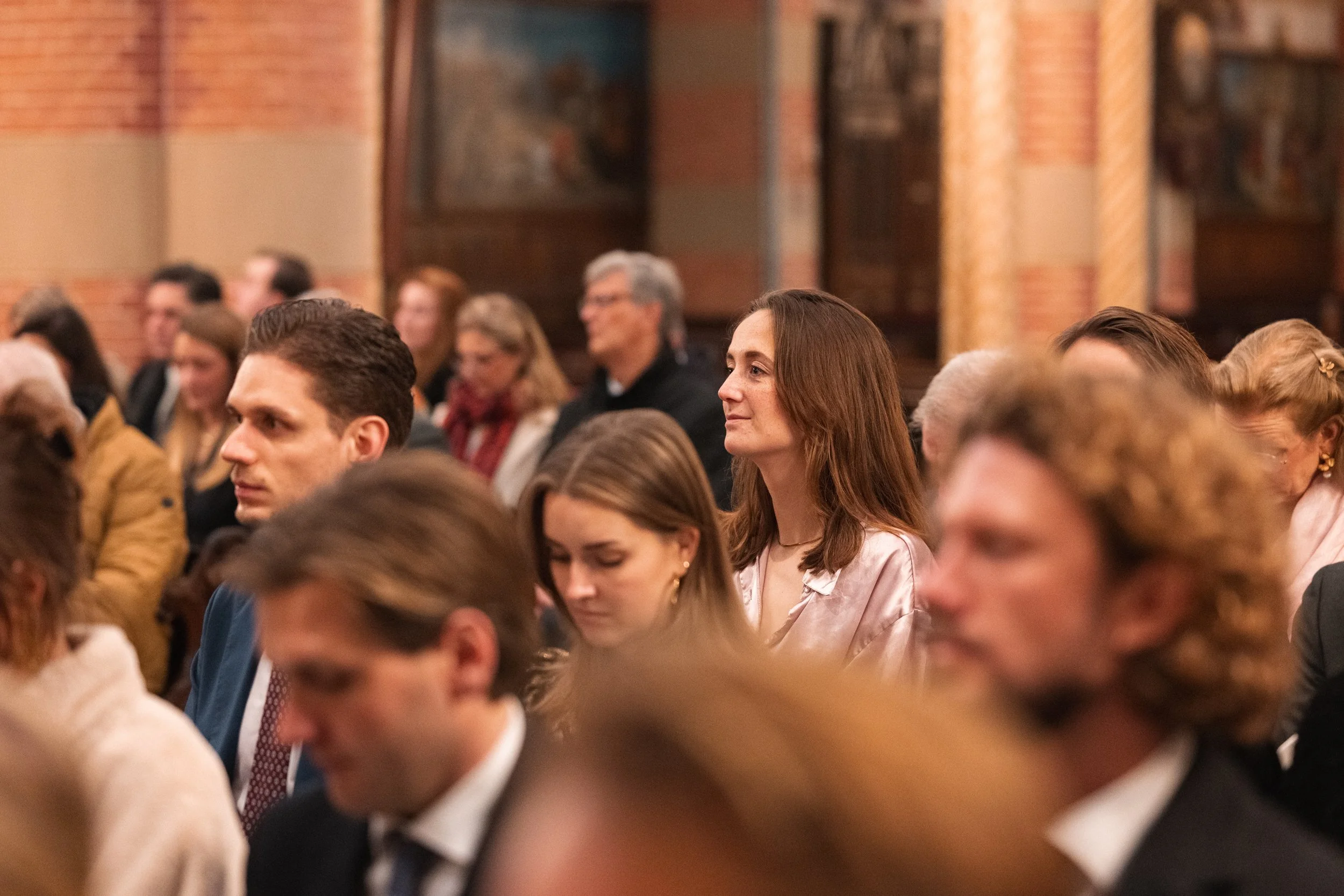 People attending a formal event or conference, sitting in rows and listening attentively.