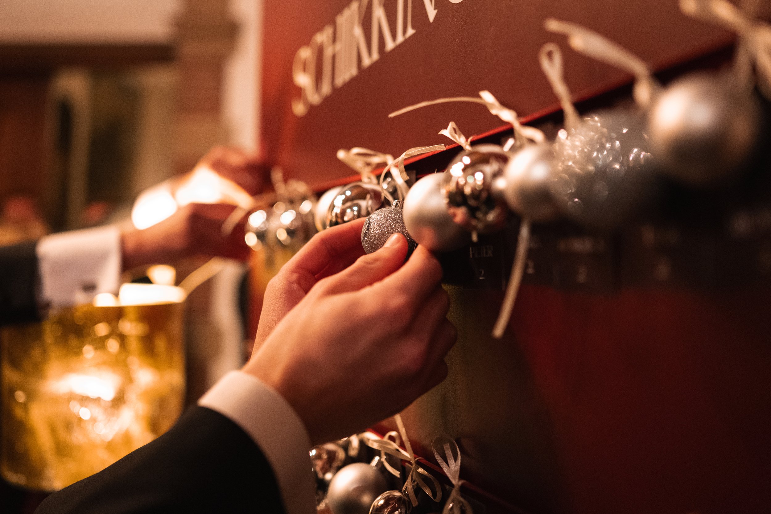 Person hanging silver Christmas ornaments on a display at a holiday market or store.