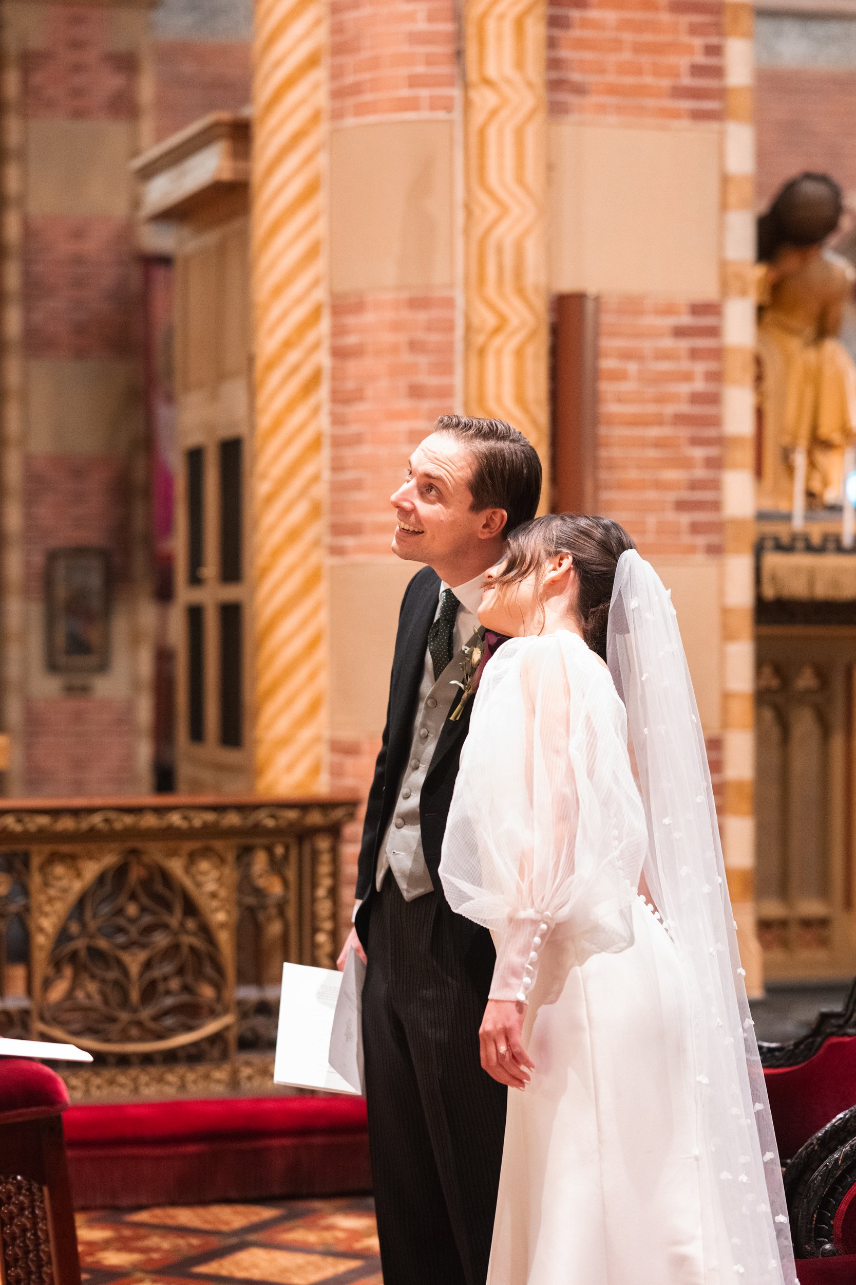 A bride and groom standing together in a church, smiling and looking up, during their wedding ceremony.