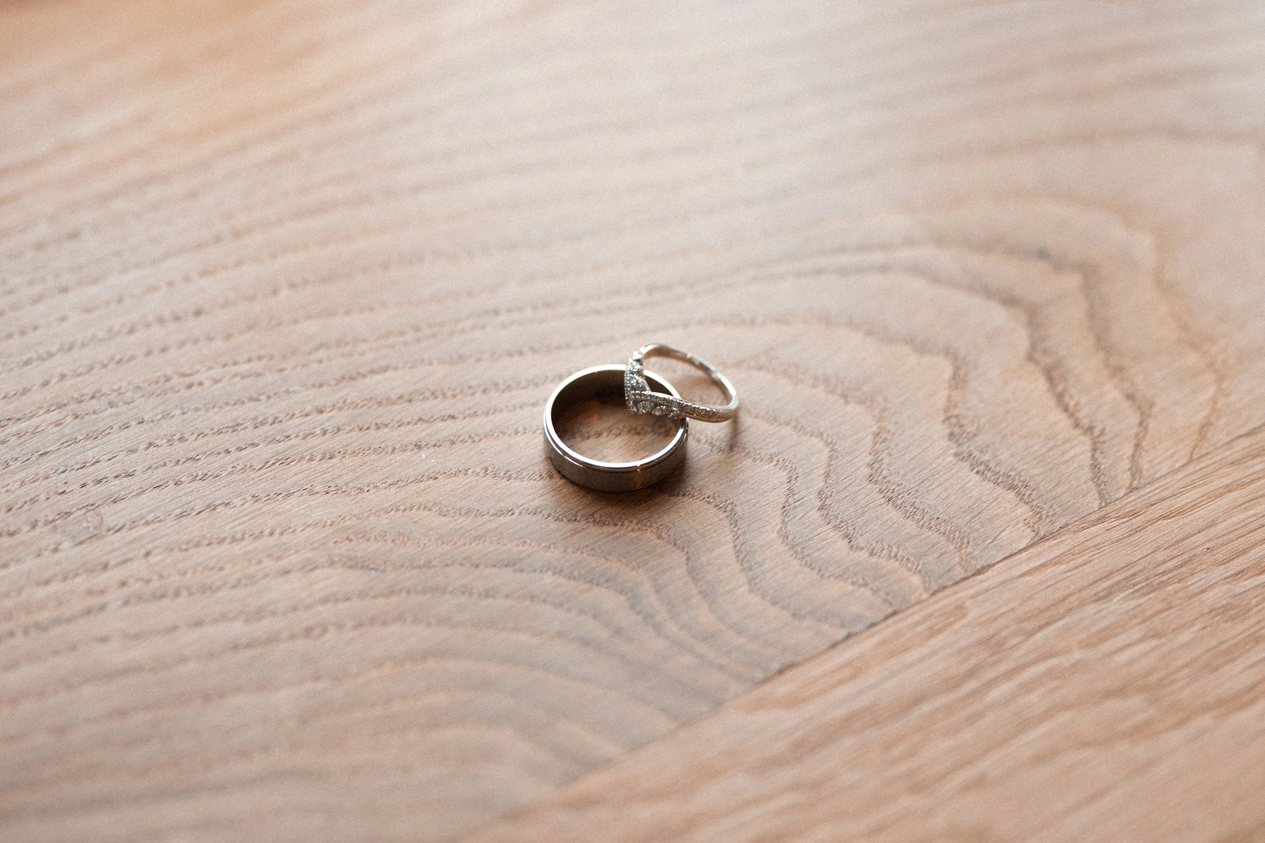 Two silver rings, one plain band and one with small embedded stones, placed on a light wooden surface.