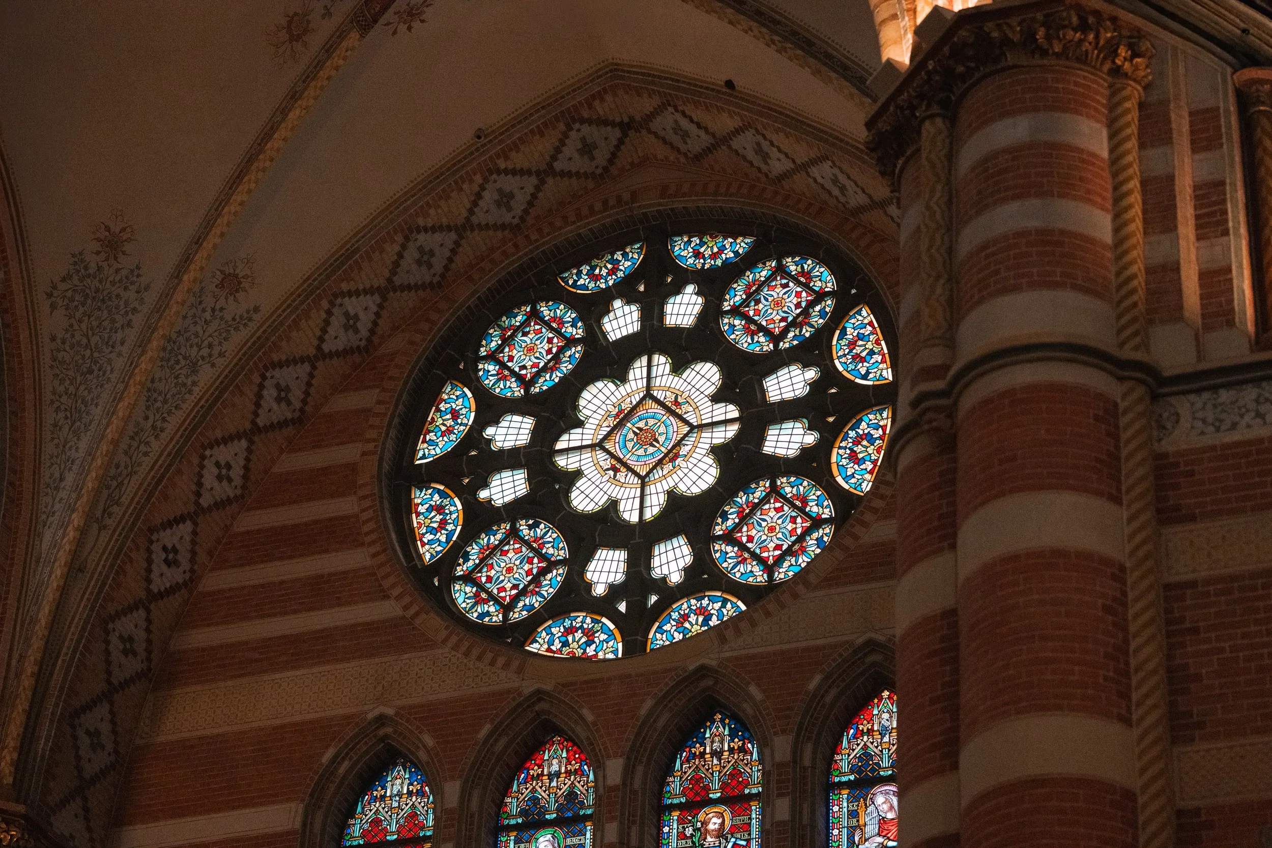 Colorful stained glass rose window in a church with brick and decorative woodwork