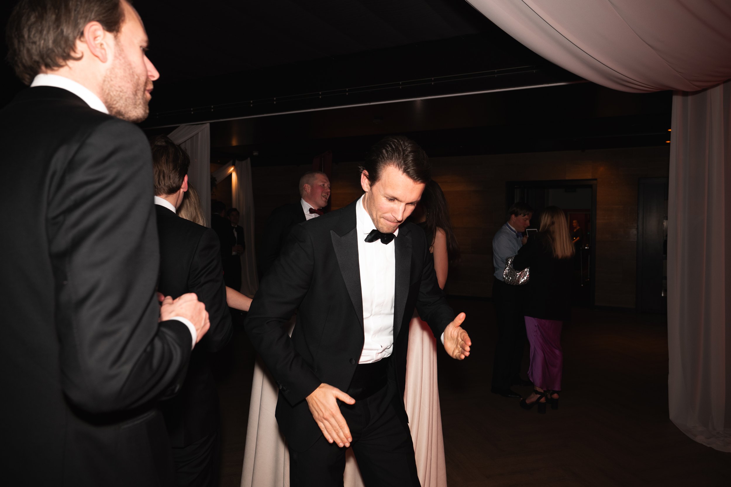 People dancing at a formal event, with men in tuxedos.