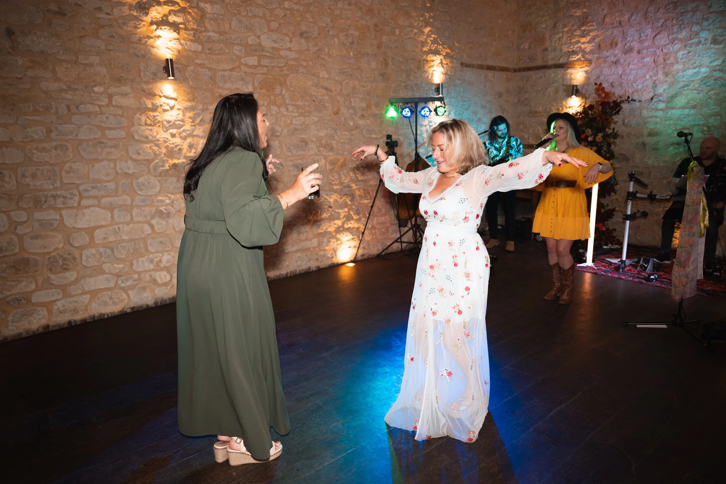 Two women dancing at a party with a band playing in the background.