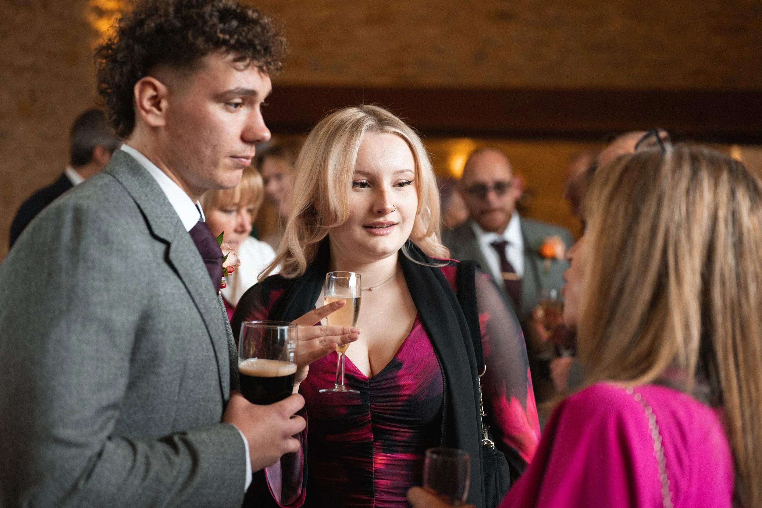 People attending a social gathering or party, holding drinks and engaging in conversation.