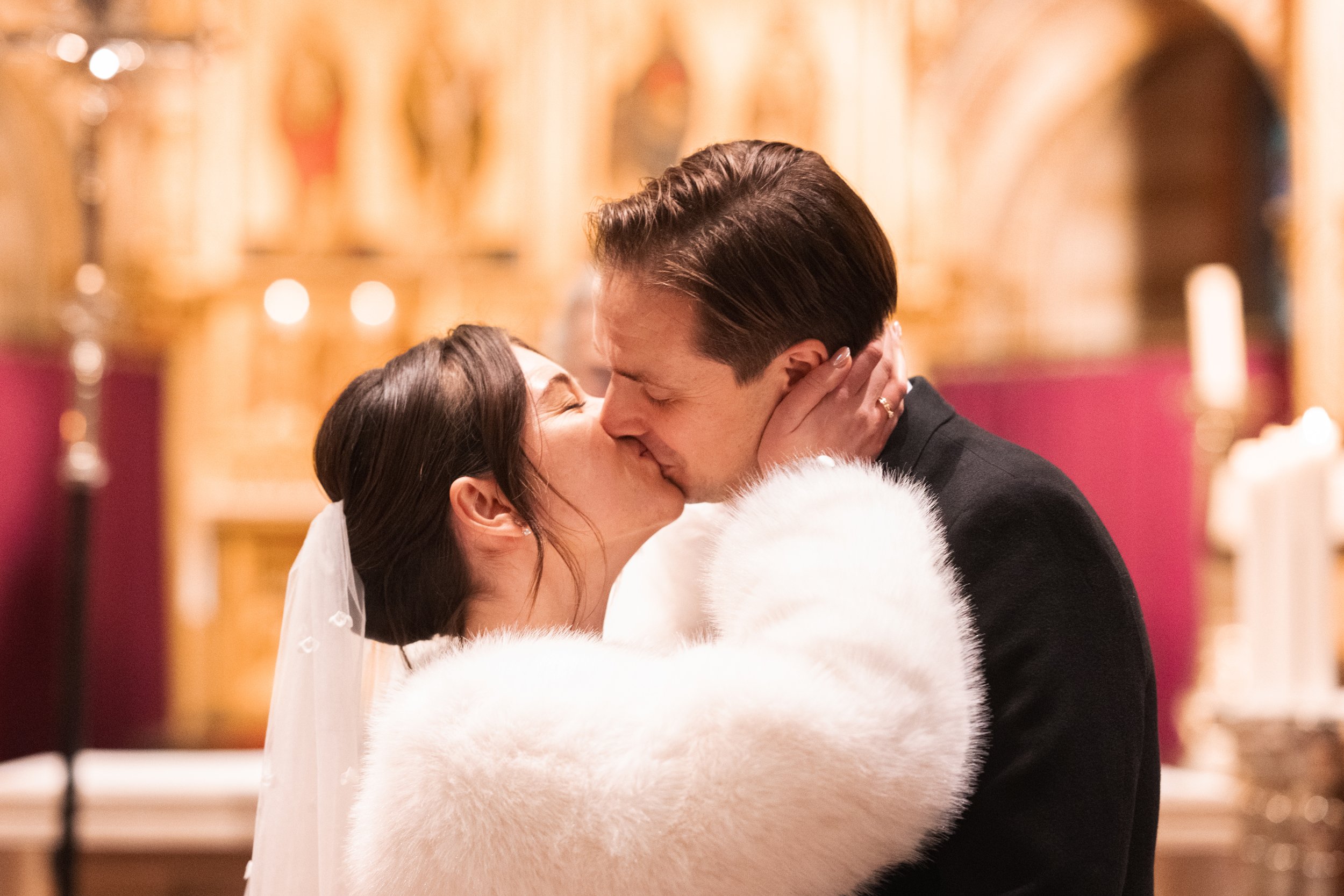 A bride and groom sharing a kiss during their wedding ceremony in a church.