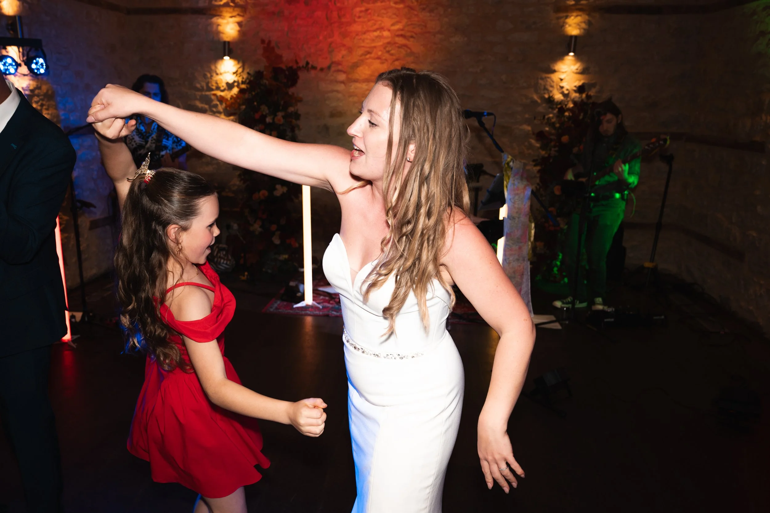 Woman in white dress dancing with girl in red dress at party