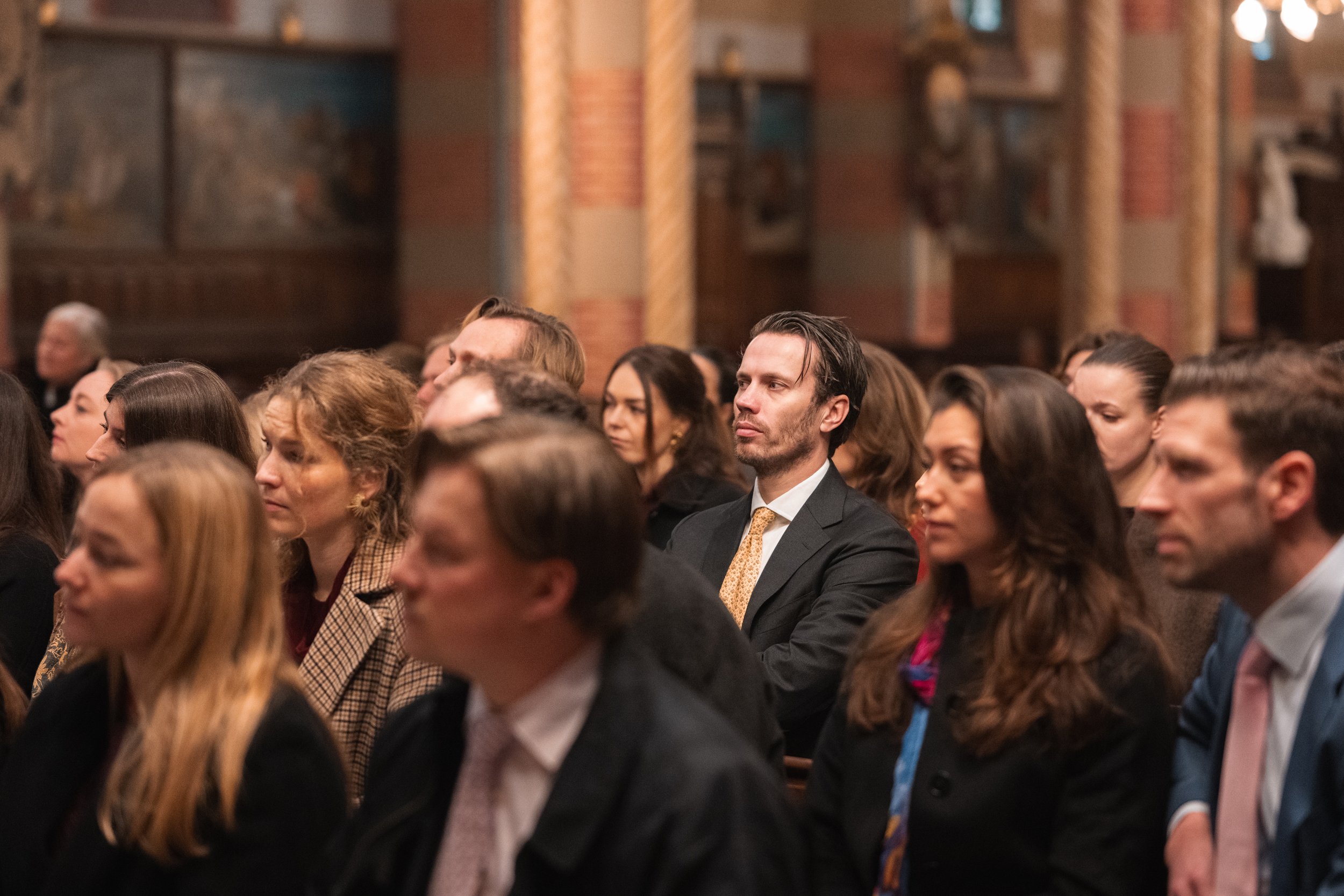 People sitting in an audience during a formal event or conference inside a decorated hall.