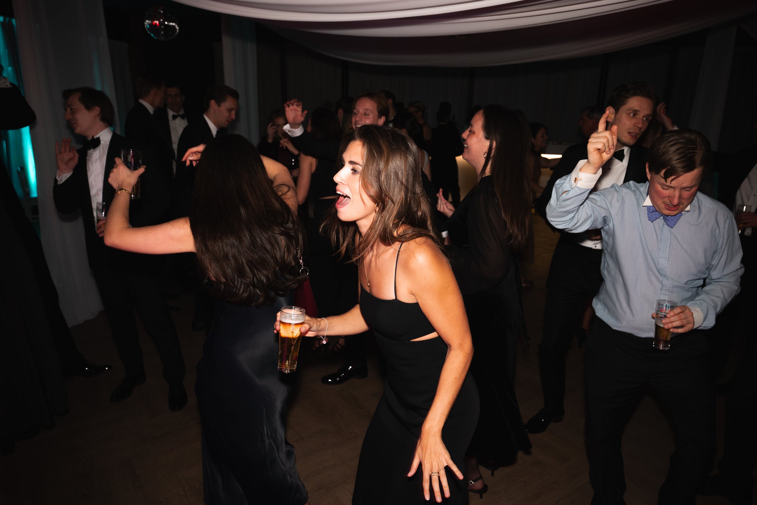 People dancing and enjoying drinks at a party in formal attire.