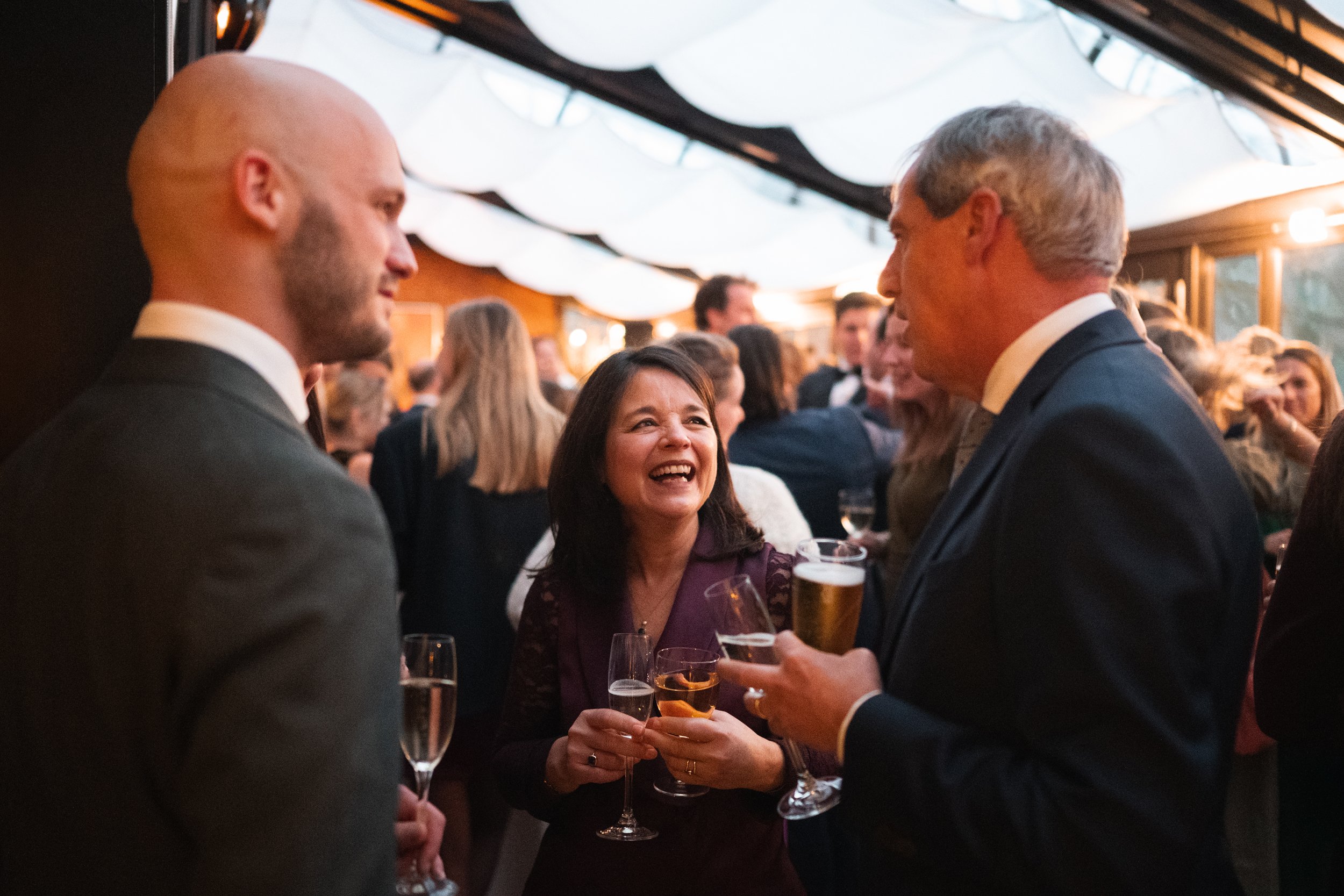 People socializing at a lively event, holding drinks and engaging in conversation