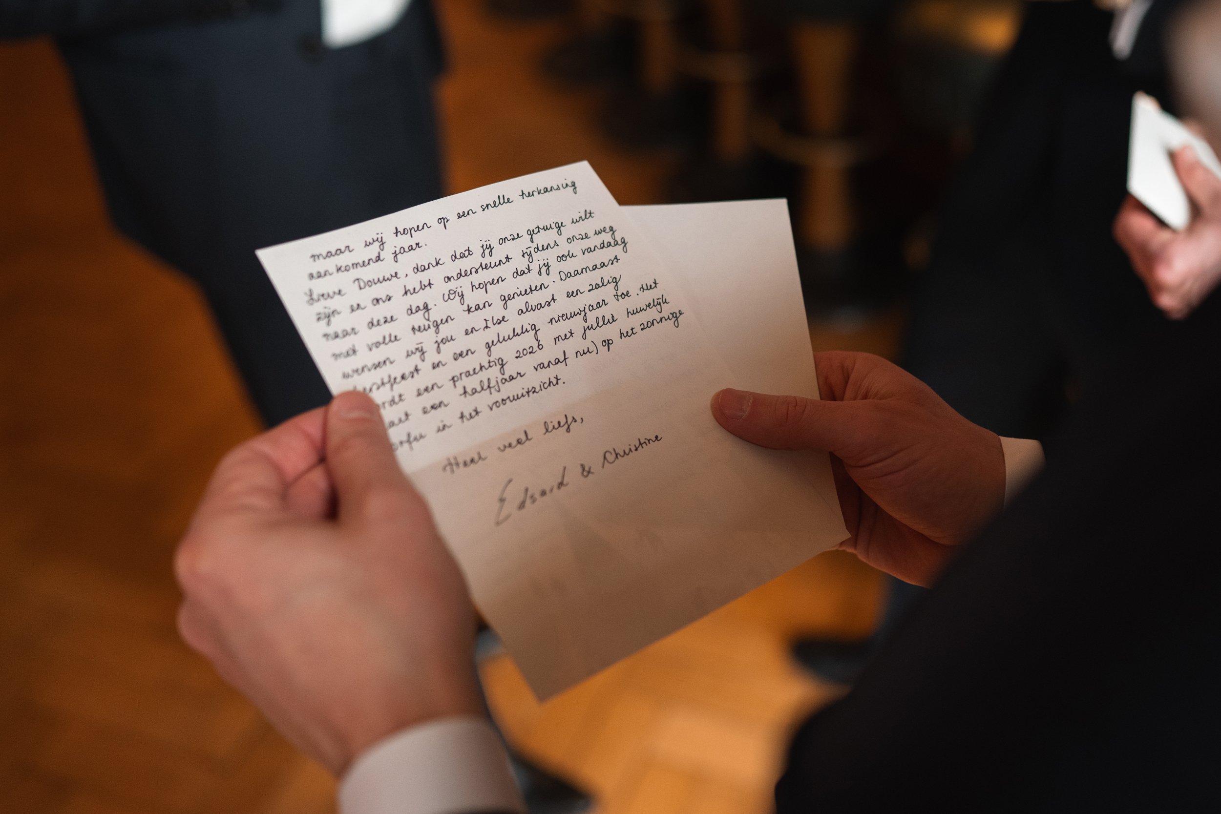Person holding a handwritten letter, with the focus on the letter, and a blurred background.