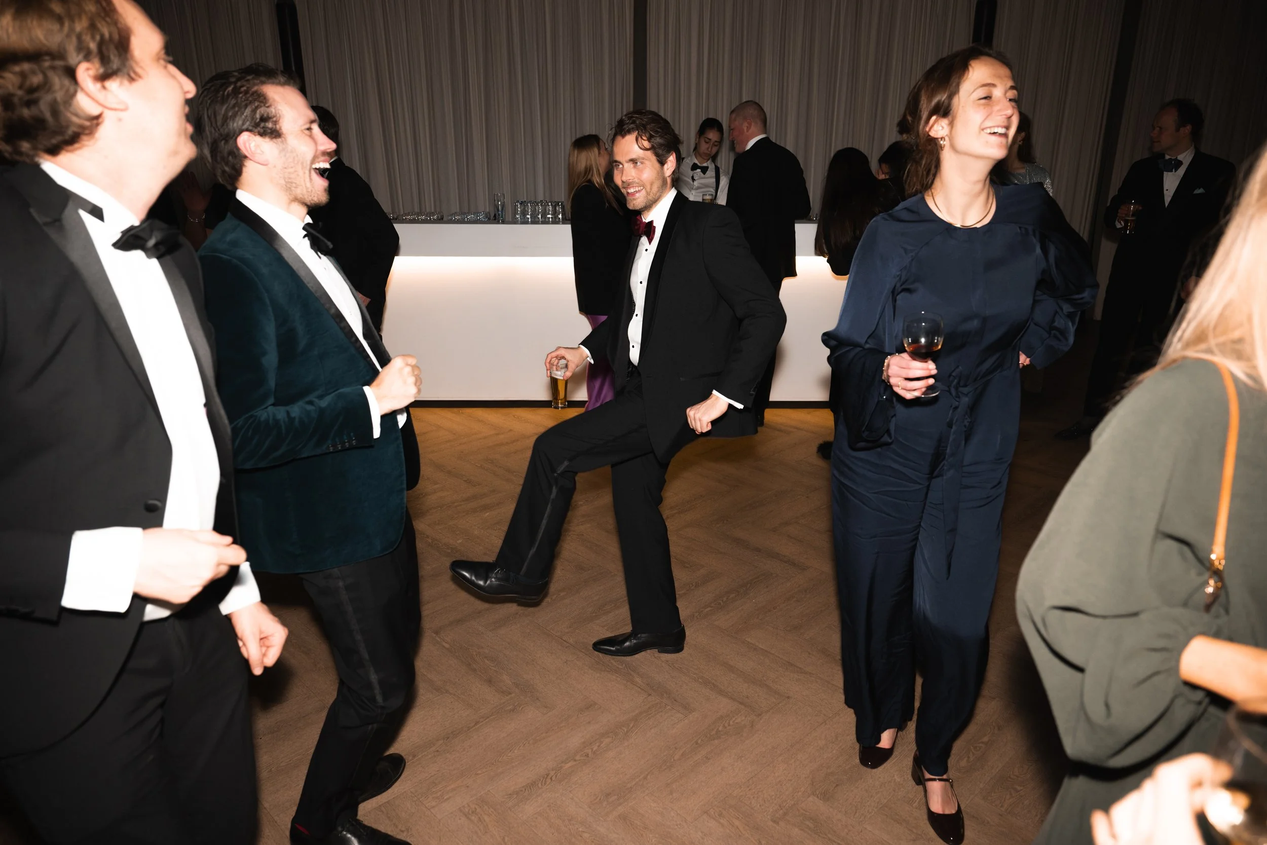 People at a formal event dancing, drinking, and socializing in a banquet hall.