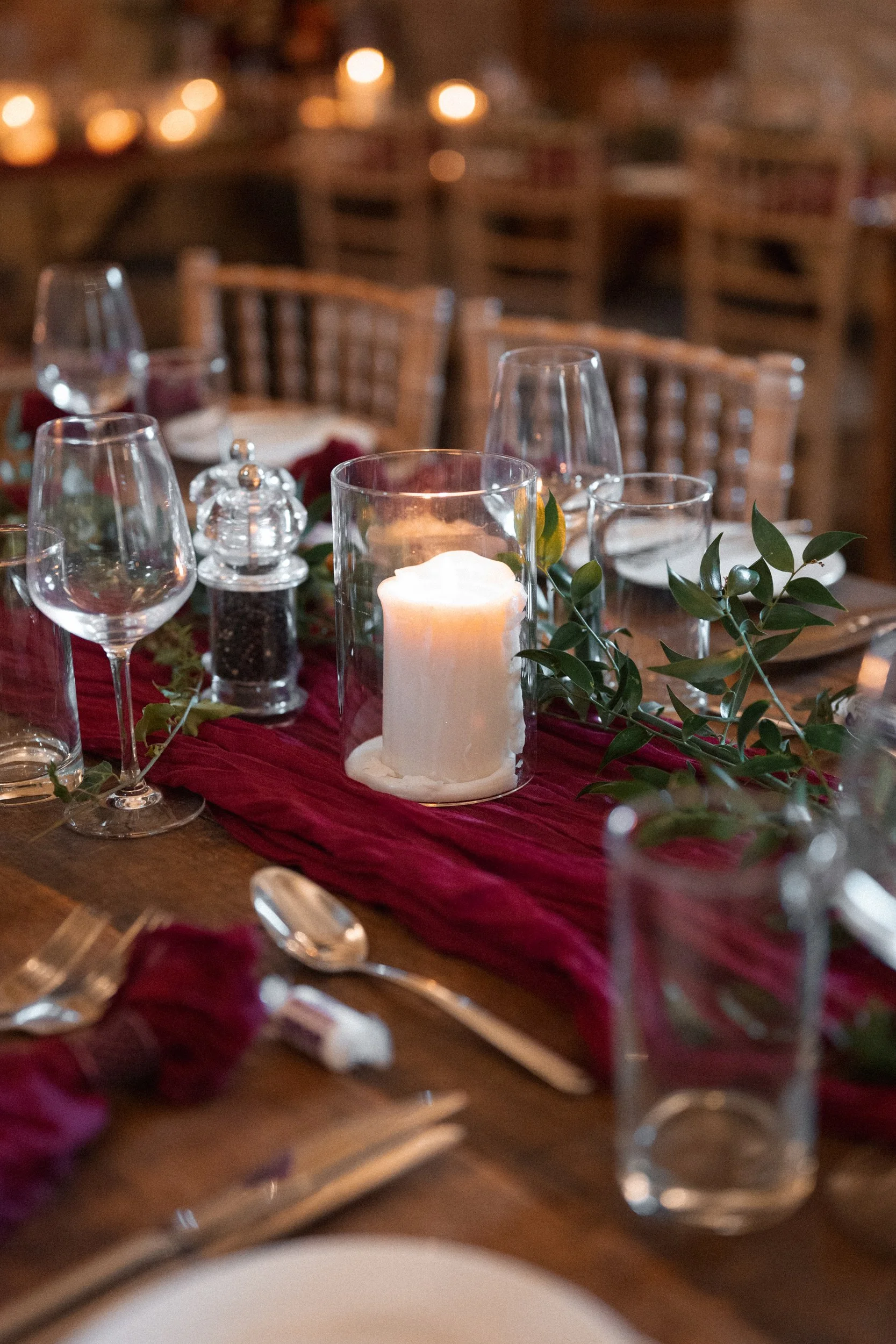 Decorated dining table with candles, wine glasses, and greenery, set for a formal event.