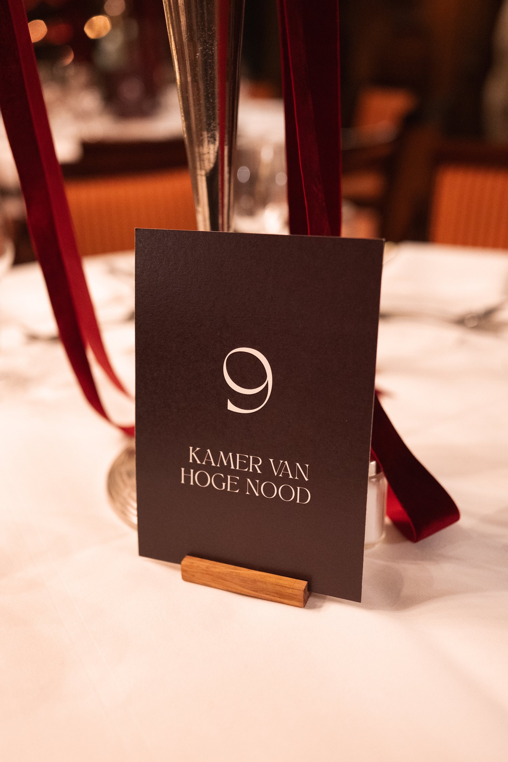 Table centerpiece with a black card displaying the number 9, set on a white tablecloth in a formal dining setting with blurred background.