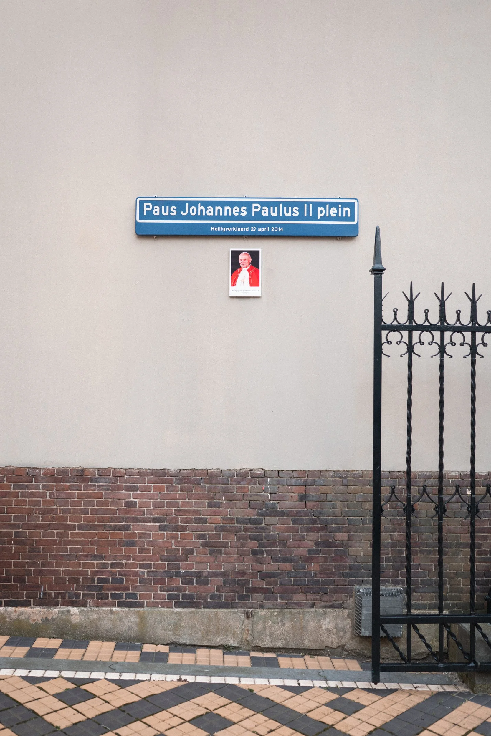Street sign reading 'Paus Johannes Paulus IIplein' with a smaller plaque below and a photograph of Pope John Paul II.
