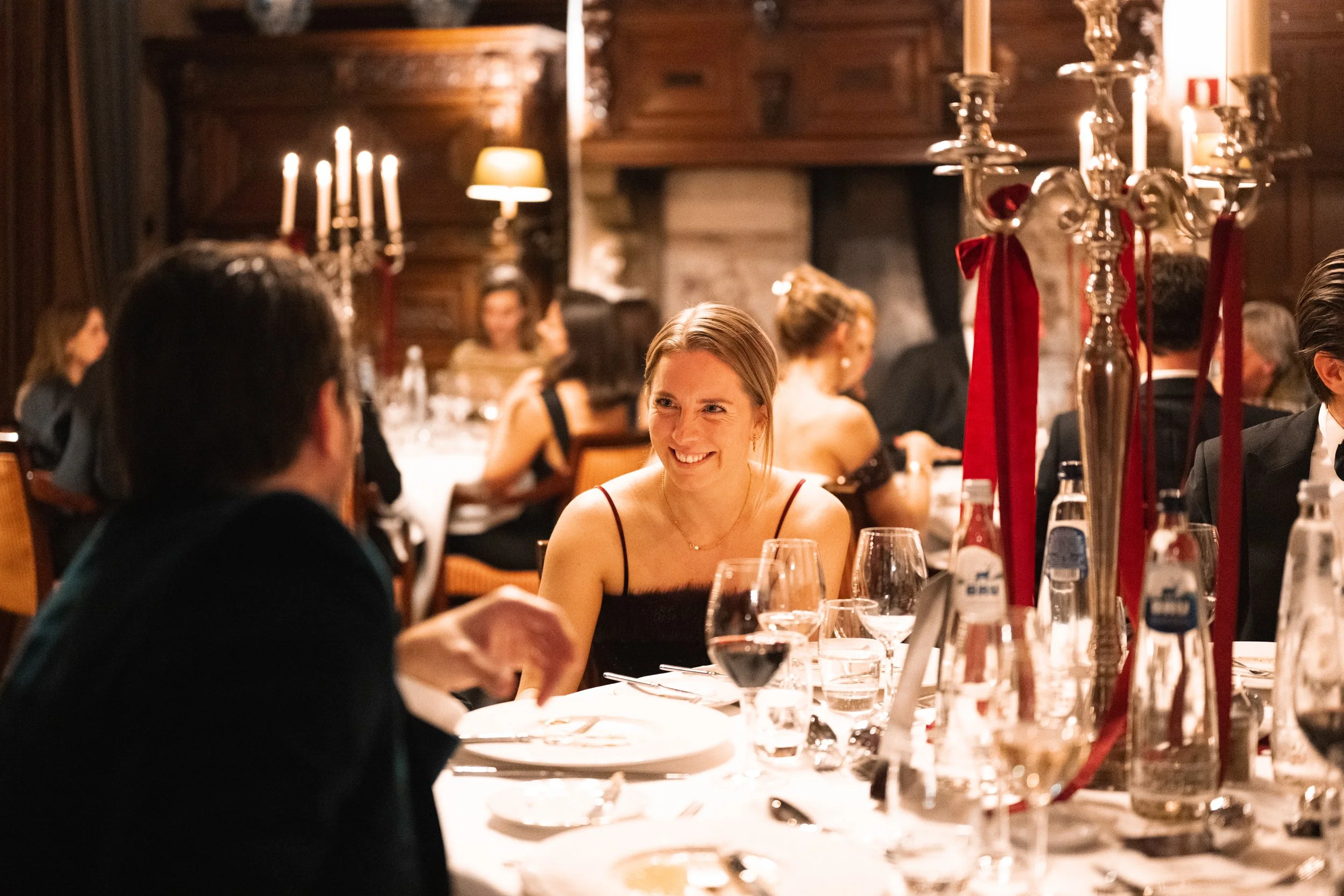 People dining at a formal event with candlelit tables and elegant decor