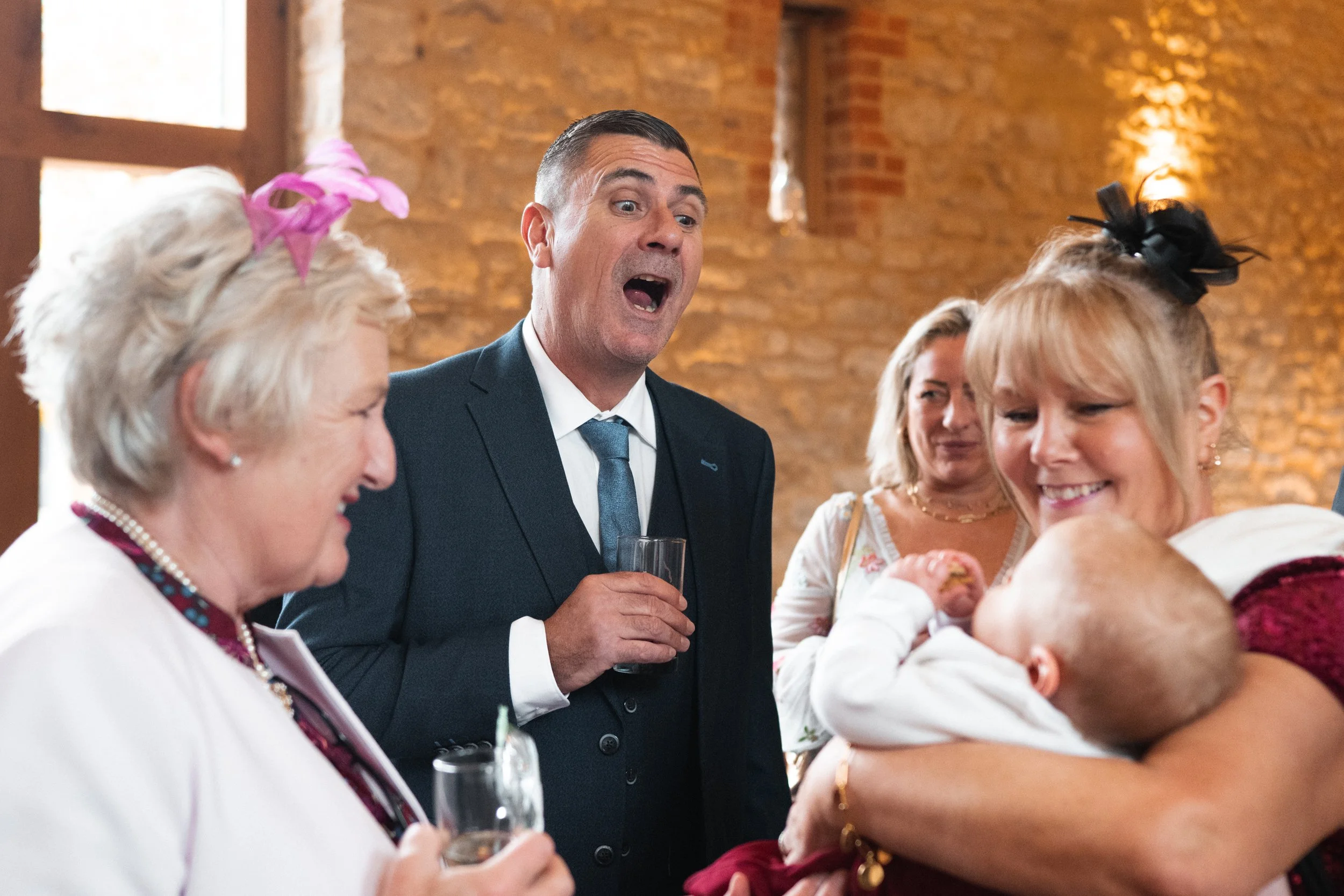 Group of adults celebrating with drinks at a social gathering, with one woman holding two children in her arms