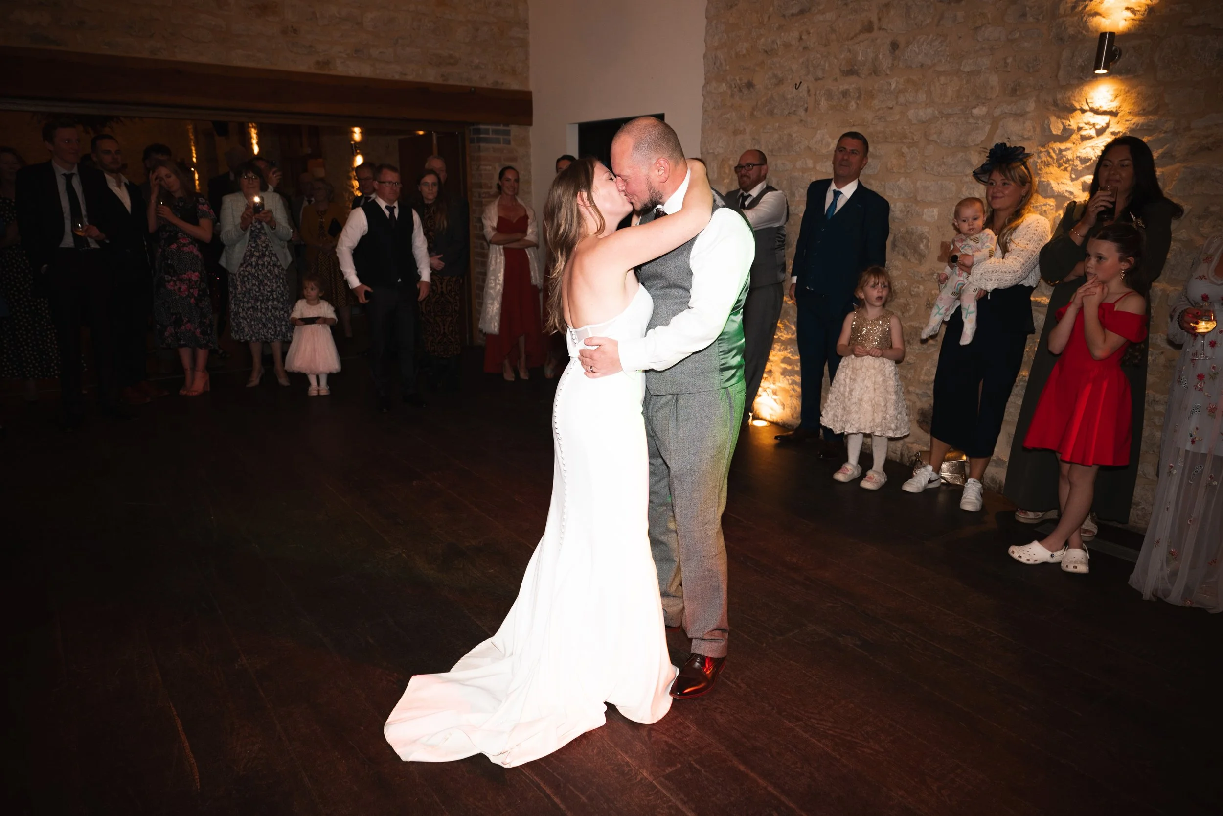 A bride and groom share a dance at their wedding reception with guests watching.