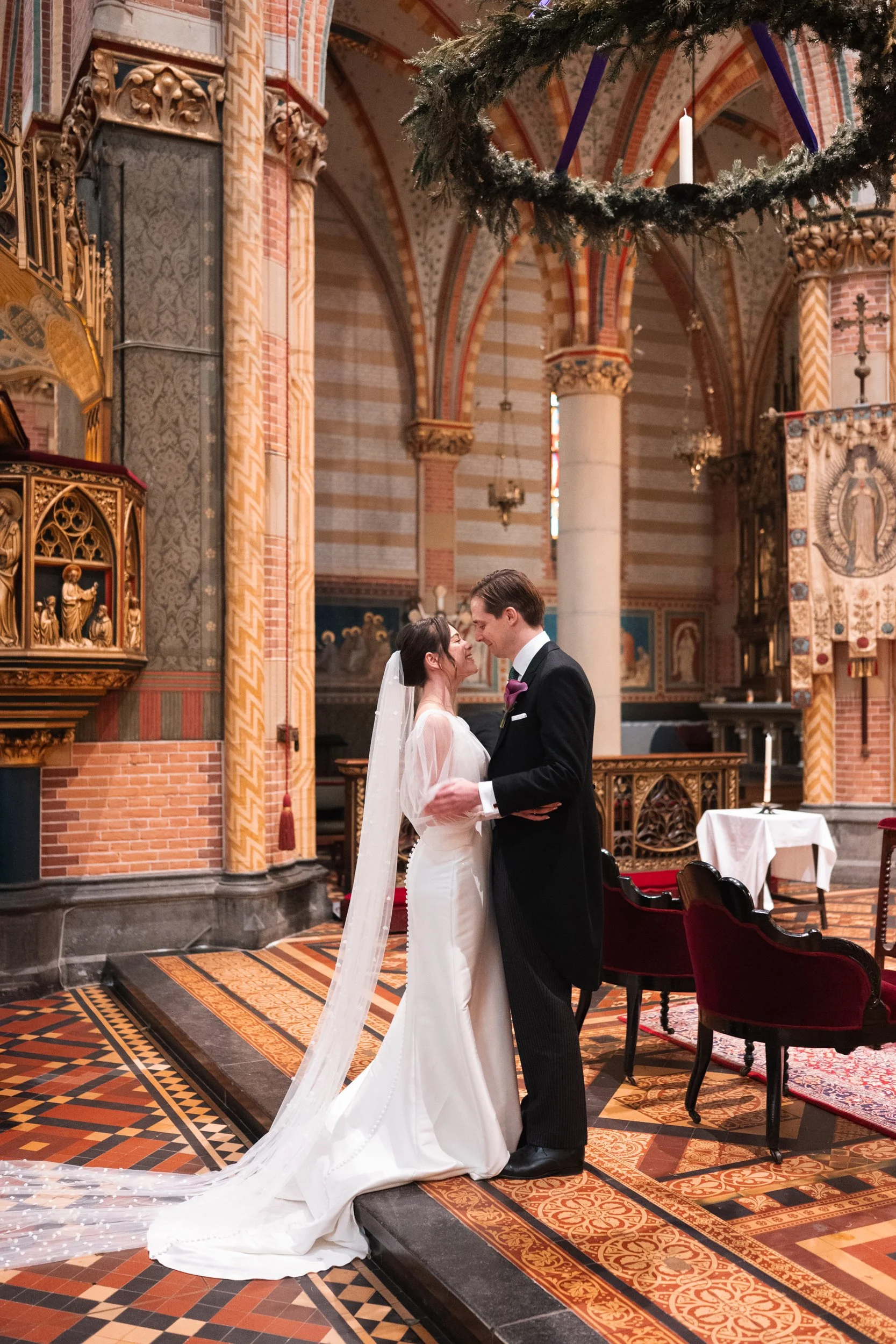 A bride and groom sharing a kiss inside a decorated church during their wedding ceremony.