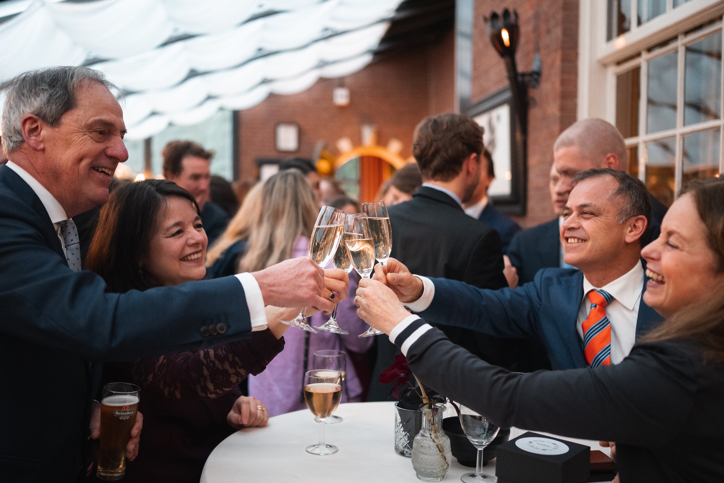 A group of people at a social gathering, raising champagne glasses in a toast at a party or celebration.