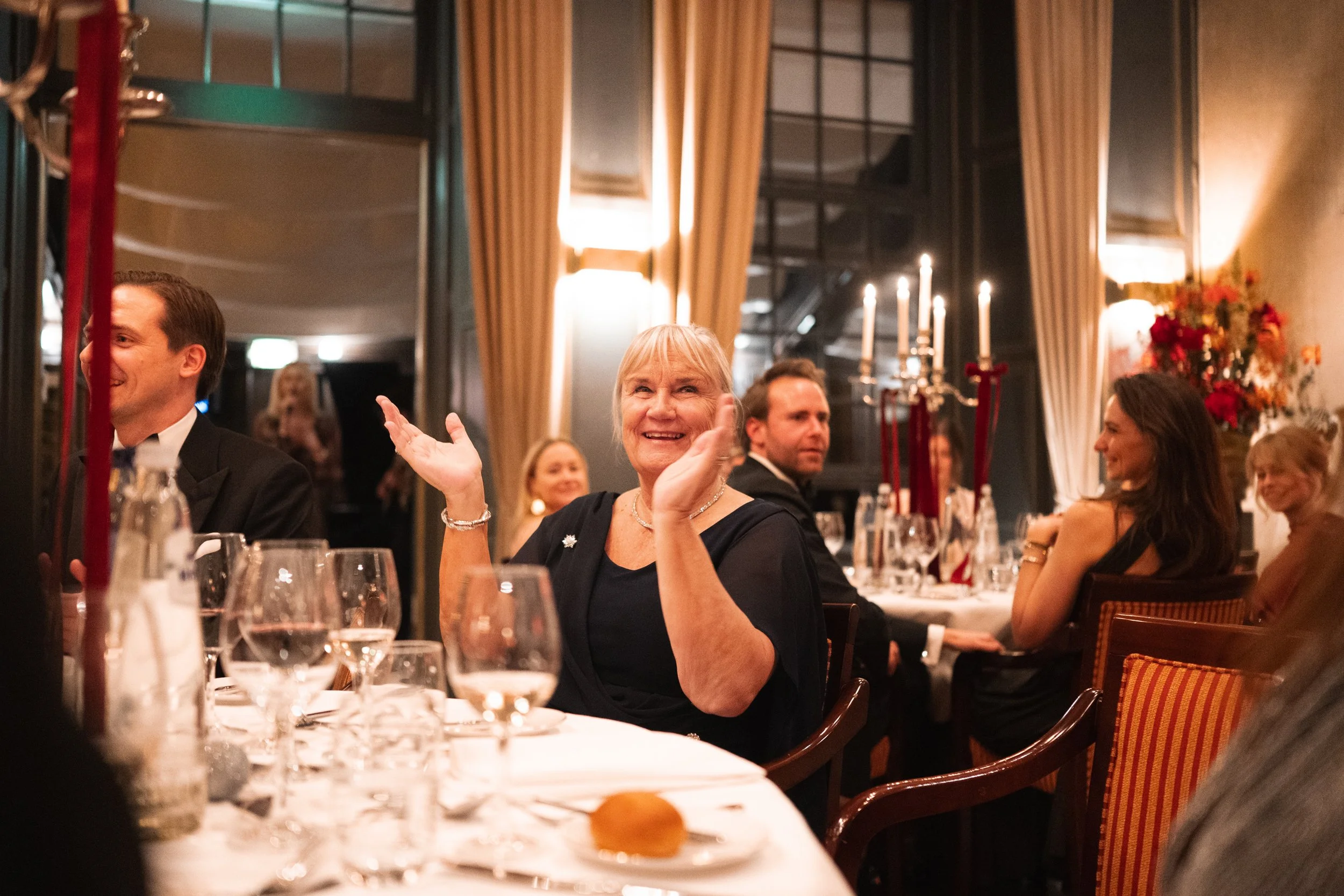 People at a formal dinner party, smiling and enjoying the event in an elegantly decorated dining room.