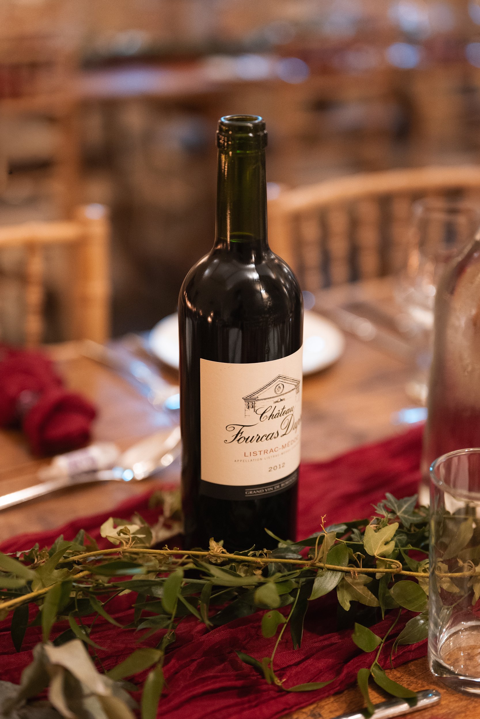 A bottle of red wine on a wooden dining table.