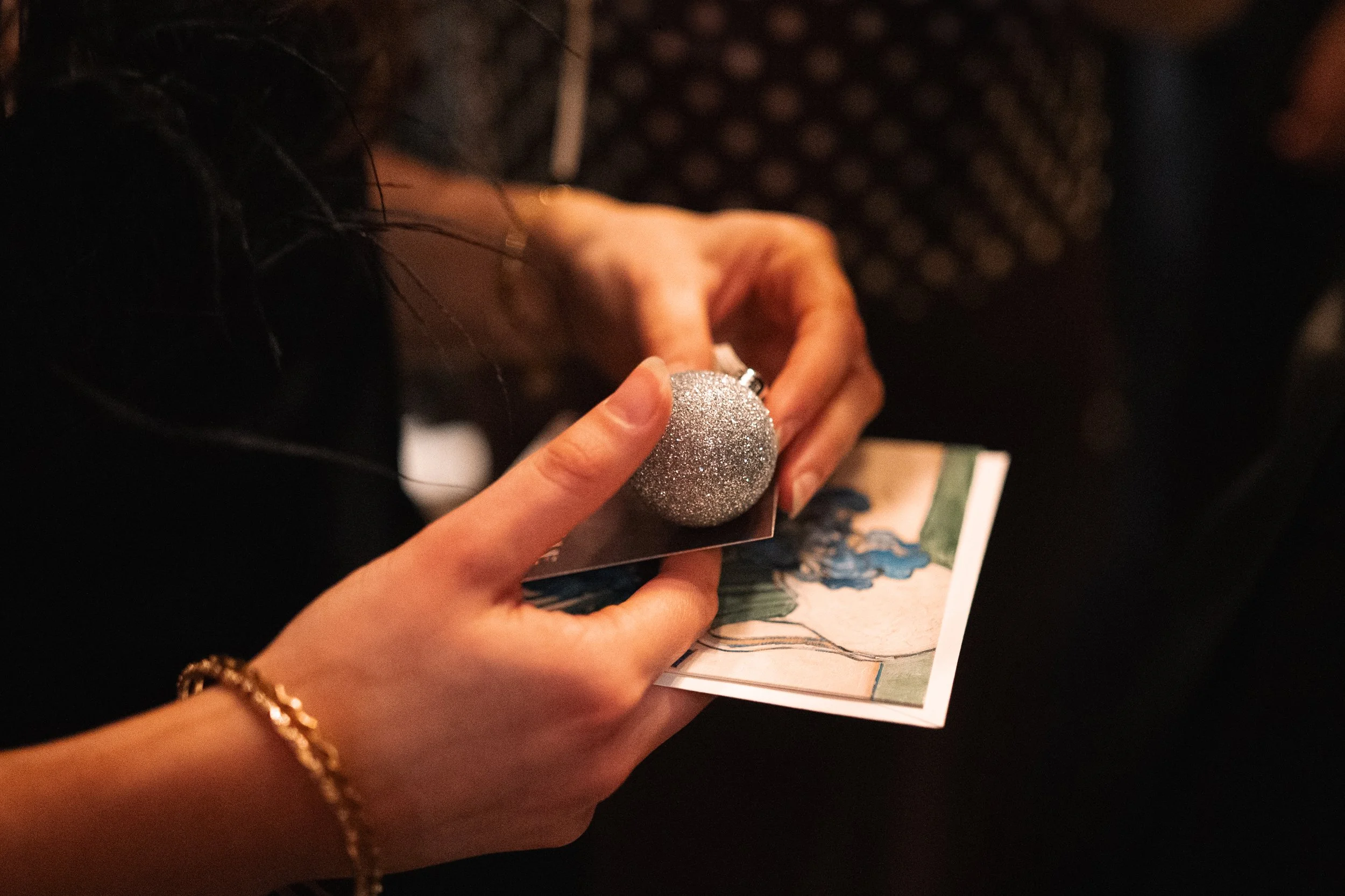 A person holding a photograph with a silver glittery ornament on top of it.