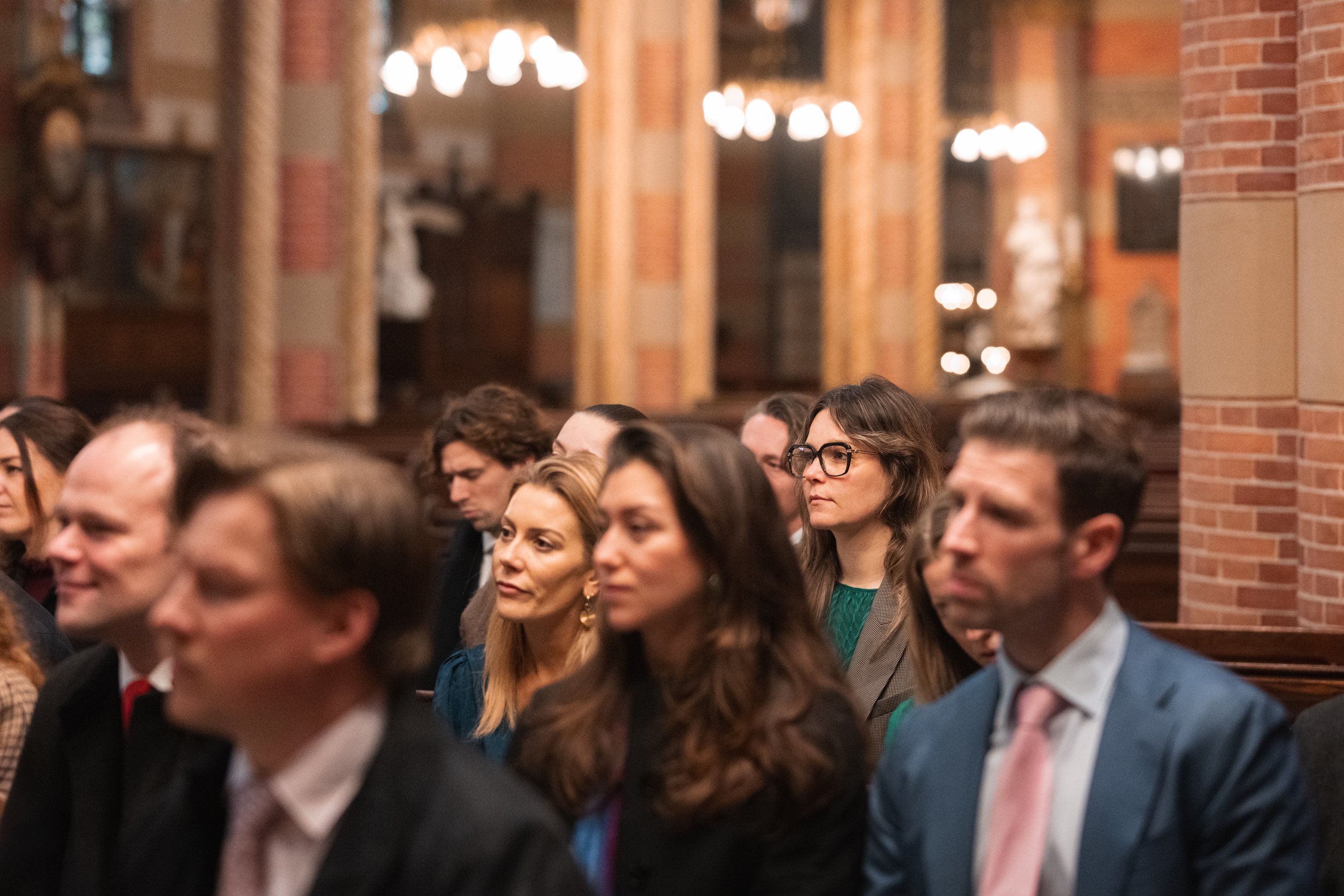 People attending a formal event or conference inside a church or historic building with brick walls and chandeliers