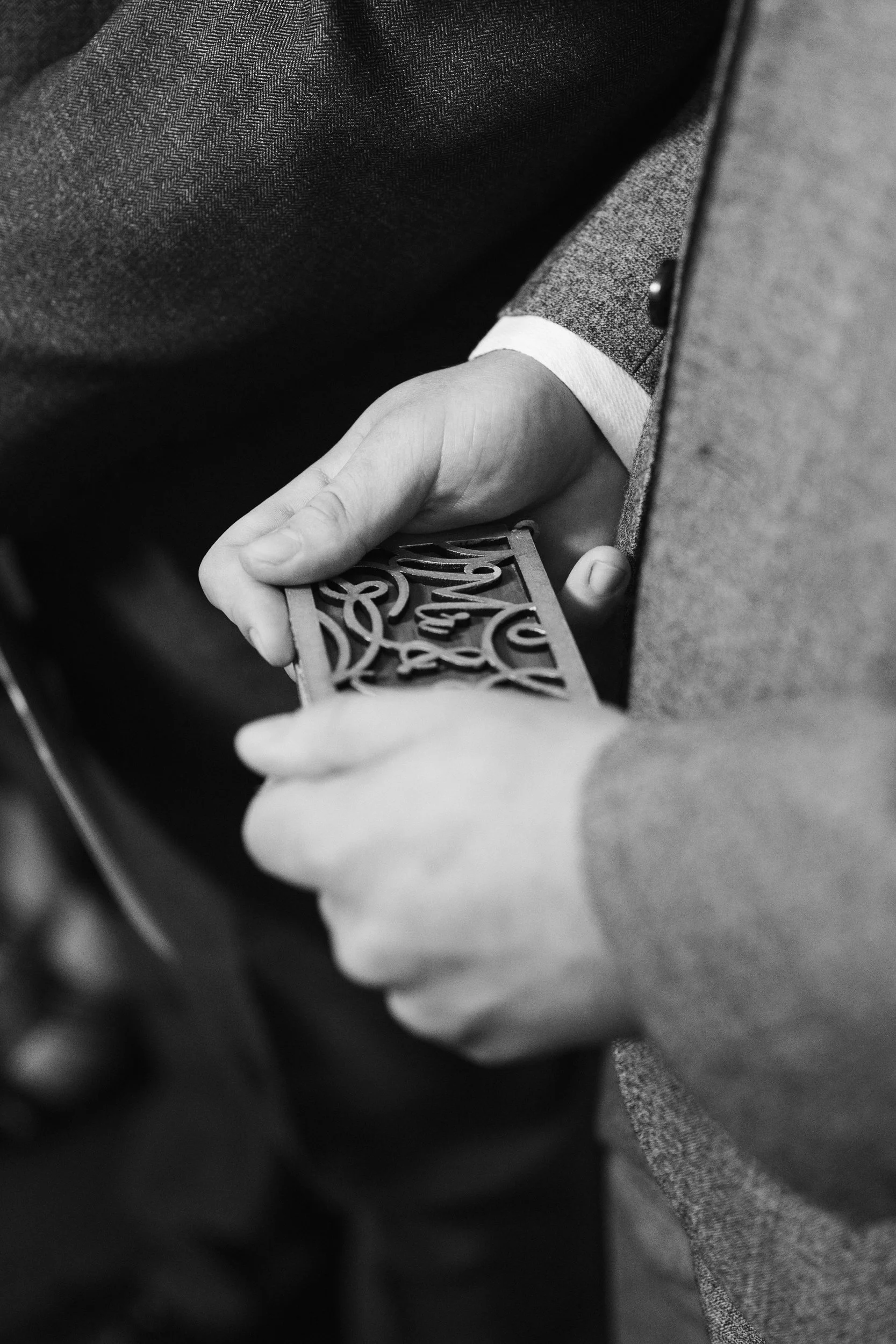 A person dressed in a suit holding a decorated card or invitation with intricate cut-out designs.