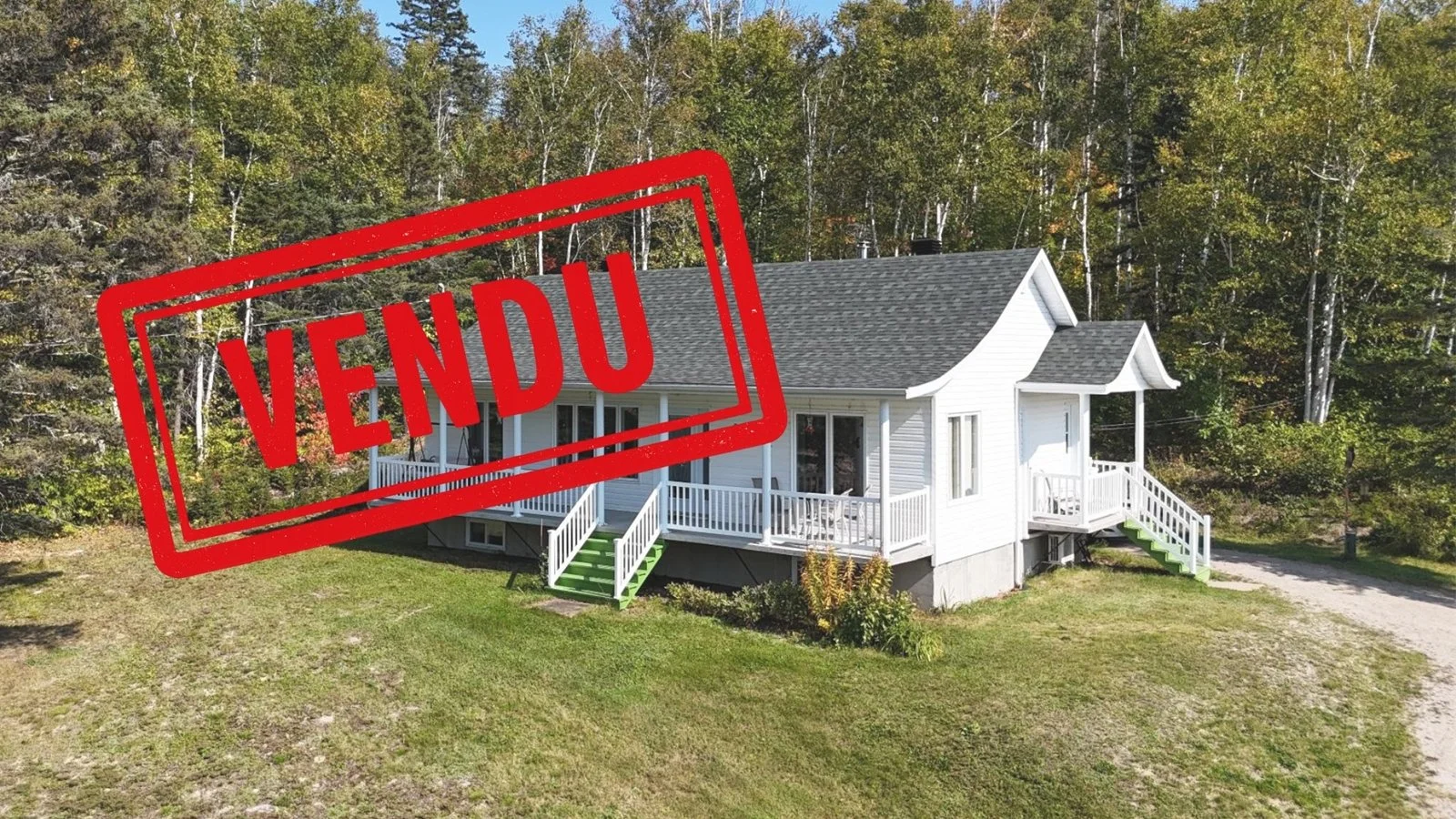Maison blanche avec un porche et des escaliers, situé à Petit-Saguenay au Bas-Saguenay, entourée d'arbres, marqué «VENDU» par Octave Société Immobilière.