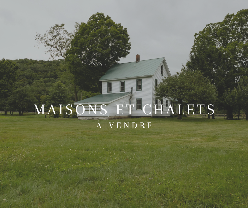 Maison blanche avec un toit en métal vert, située dans un grand espace herbeux avec des arbres alentours, annonce à vendre de maisons et de  chalets.
