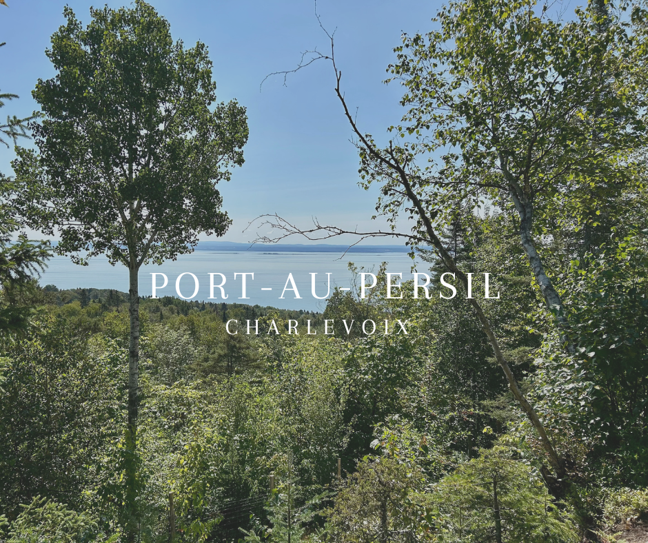 Une vue de la forêt dense avec un étang ou une mer en arrière-plan, le ciel est clair et ensoleillé, avec le texte "PORT-AU-PERSIL CHARLEVOIX" en surimpression.