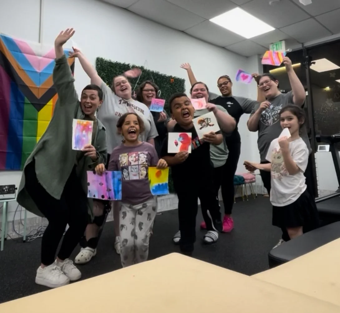 A person holding up their finished painting at an art therapy workshop, symbolizing resilience and healing in Roland Park, Maryland.