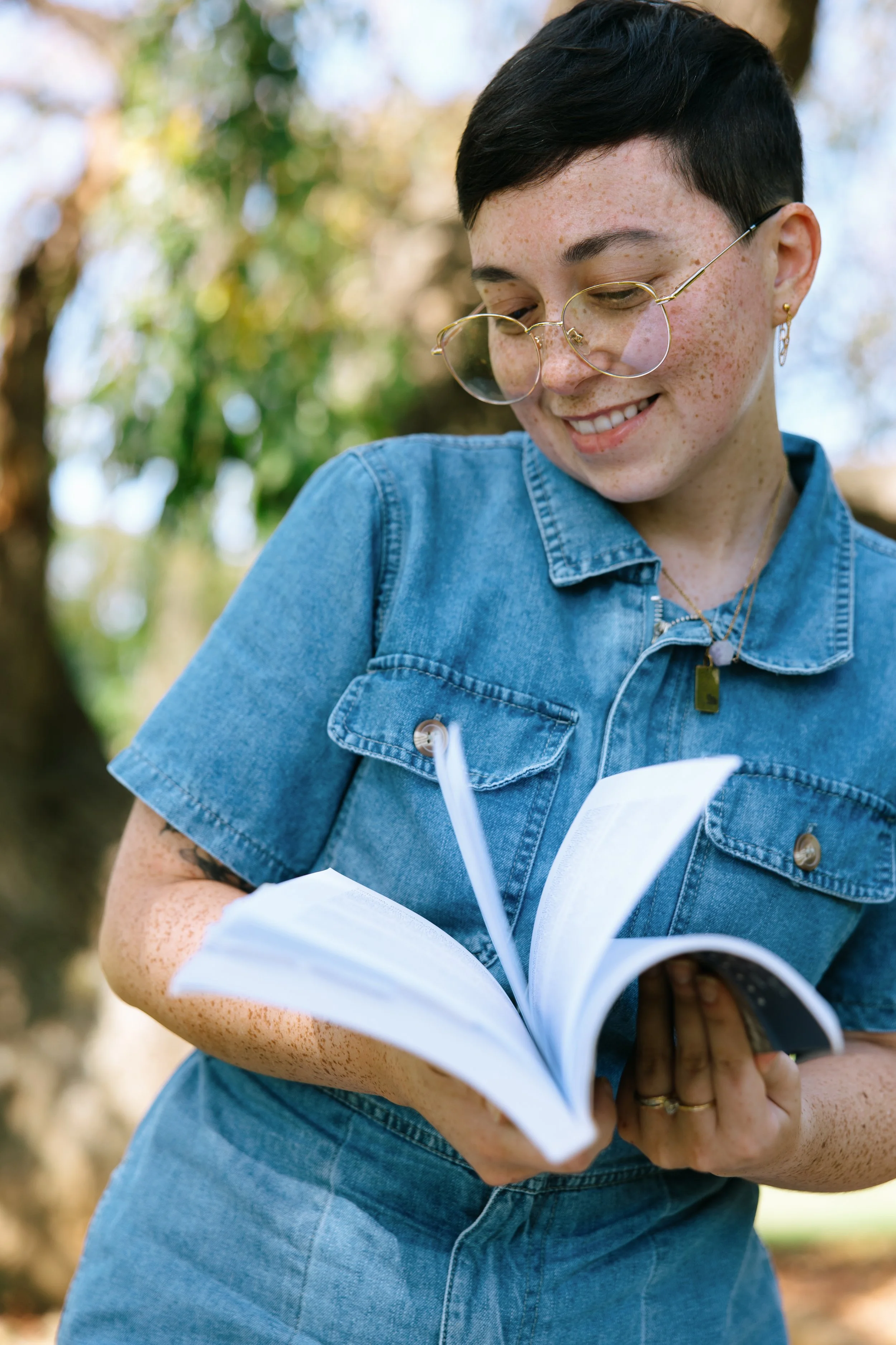 Kristy Leone is a licensed art therapist in Maryland, helping clients with OCD, anxiety, and sleep disorders in Maryland. Kristy is holding a therapy book outdoors during an art therapy session.