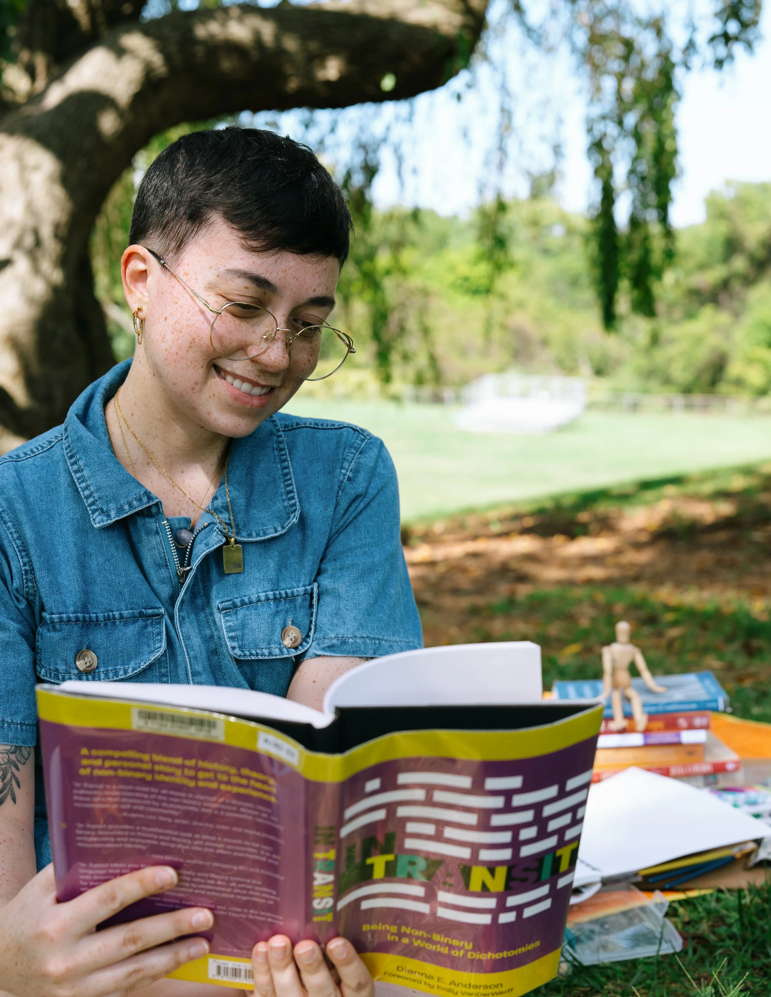 Nonbinary Art Therapist Kristy Leone reading a mental health book outside in Maryland.