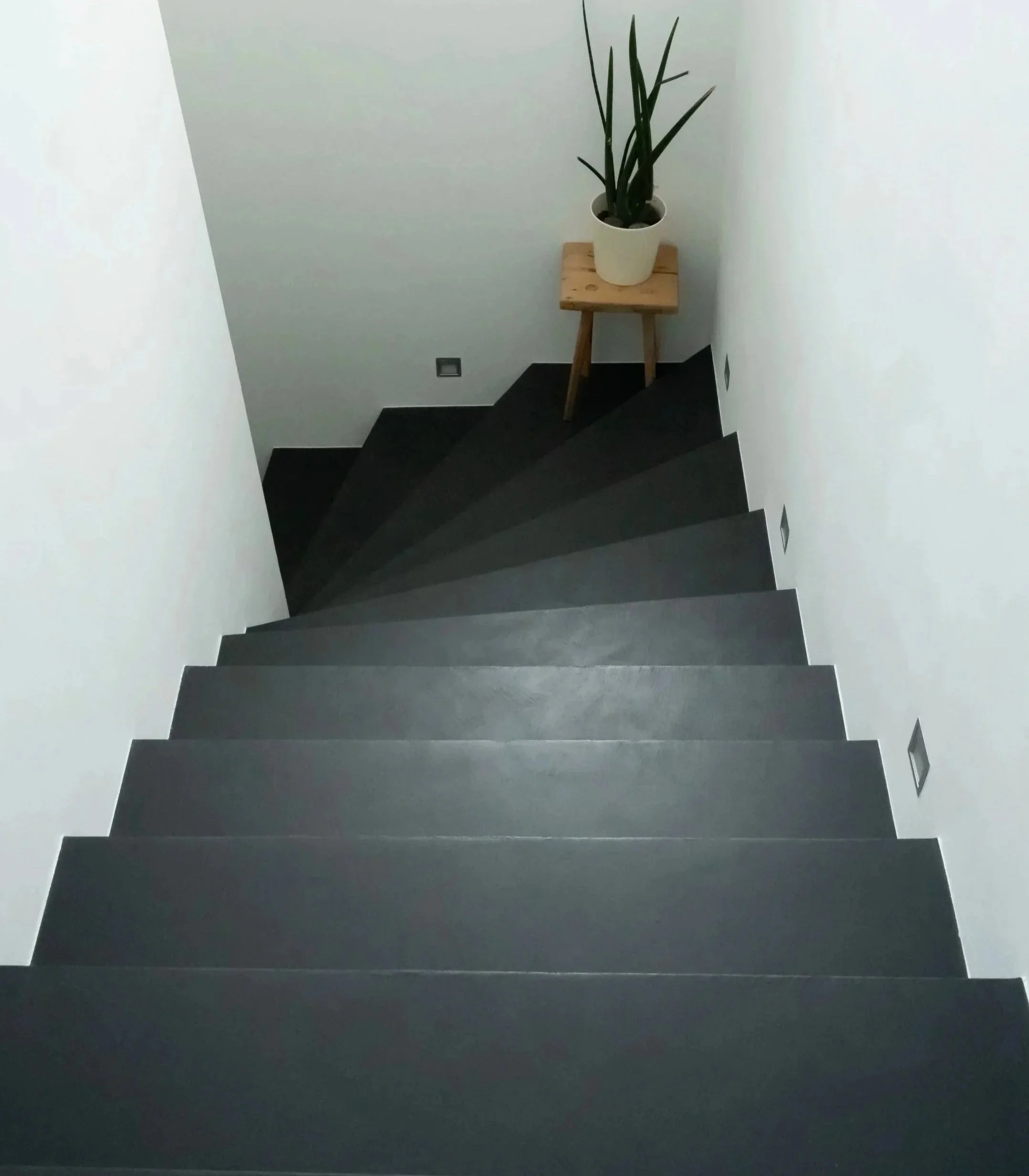 Bestehender Fliesenboden auf Treppe mit fugenloser Beschichtung überarbeitet. Umbau Surselva.