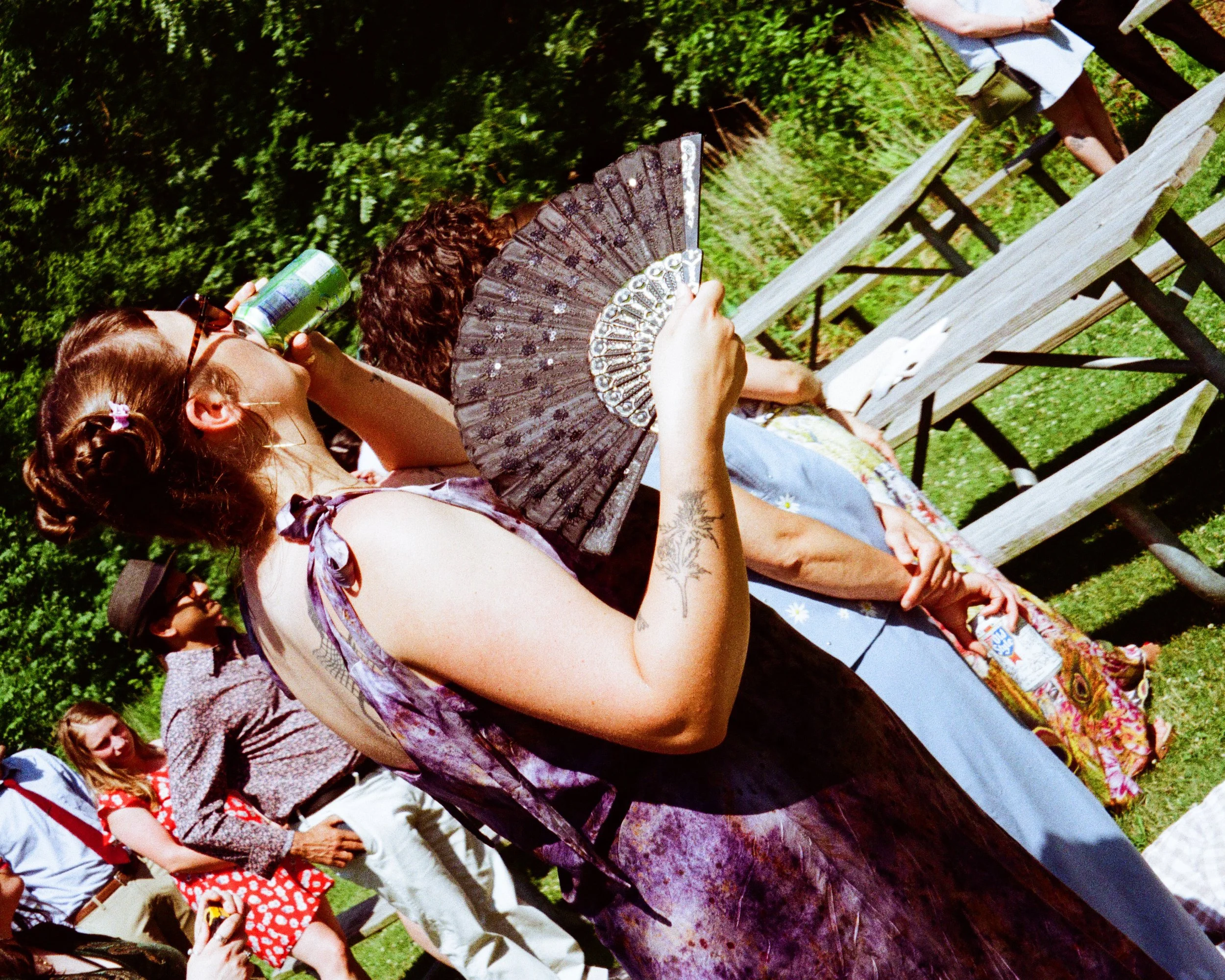 film image of a person holding a hand fan at an outdoor summer wedding
