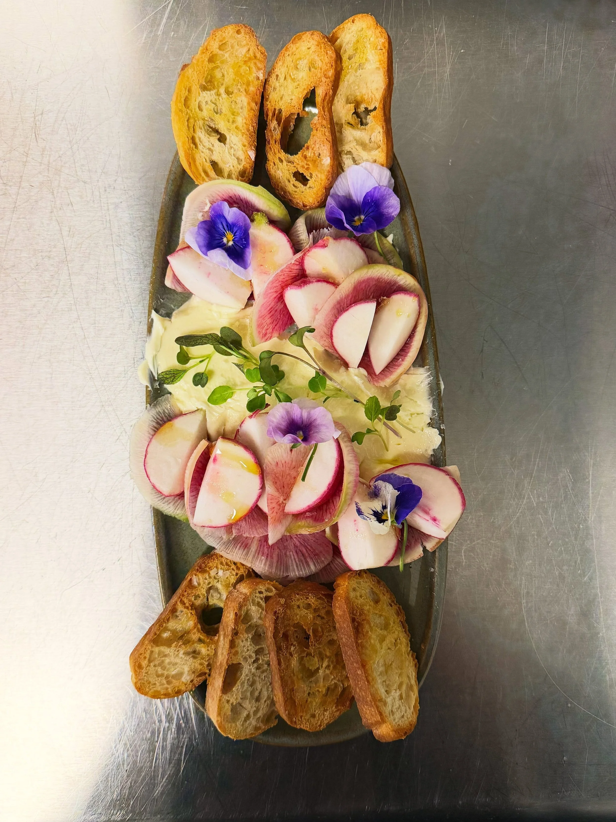 Isn&rsquo;t she pretty? 😍 Our house-made #culturedbutter with seasonal radish, crostini and a touch of floral whimsy 🌸🤤