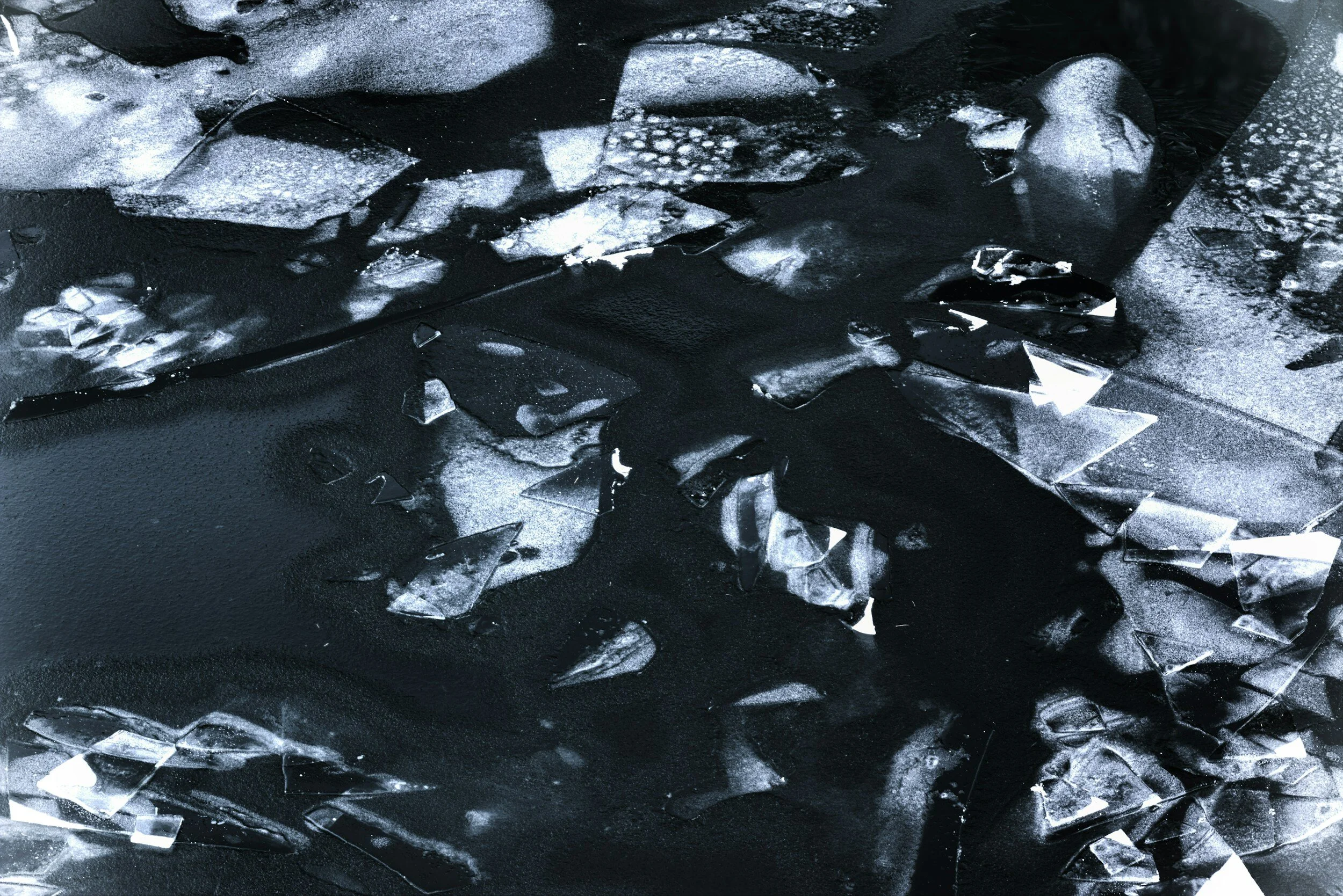 Pieces of broken glass scattered on a dark surface.