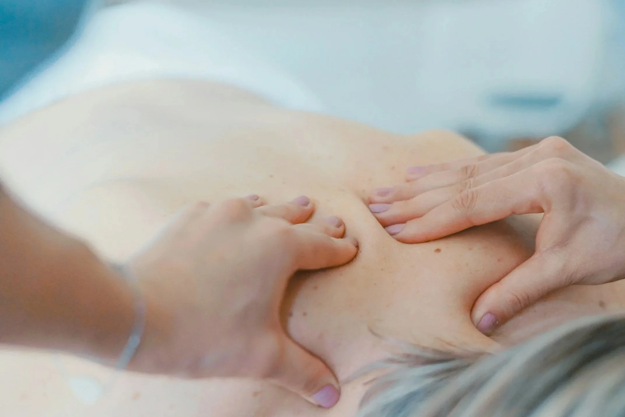 Close-up of a massage therapist's hands applying a massage to a person's back.