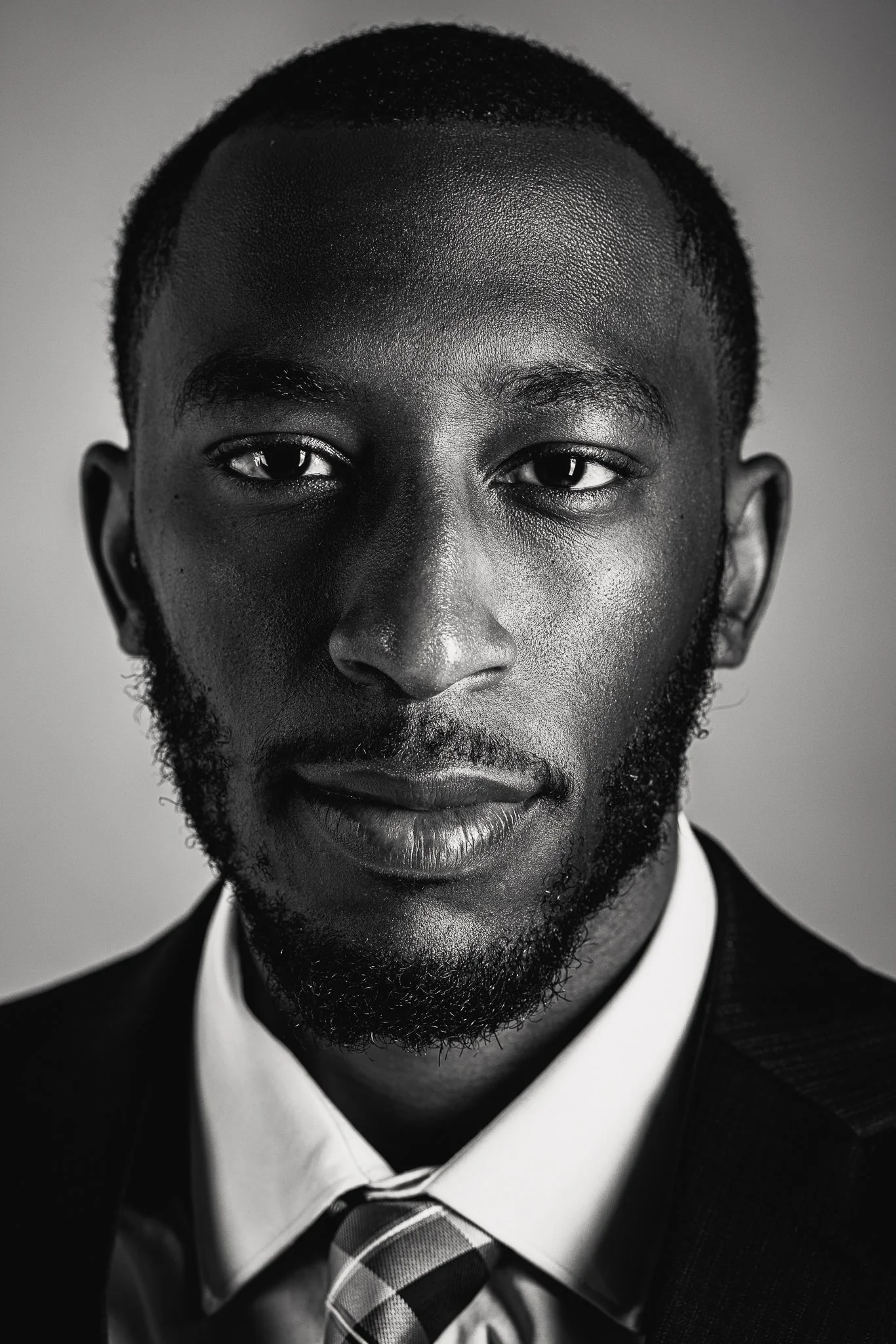Black and white portrait of a man with a beard, wearing a suit and tie, looking directly at the camera.