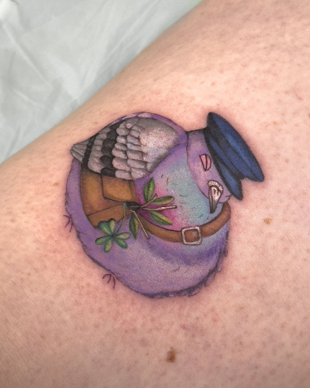 Whimsical tattoo design of a happy sleeping pigeon wearing a postman hat, with a small postal bag filled with shamrock and leafy branches. Charming Irish-inspired tattoo artwork with playful, cosy details and a illustrative style