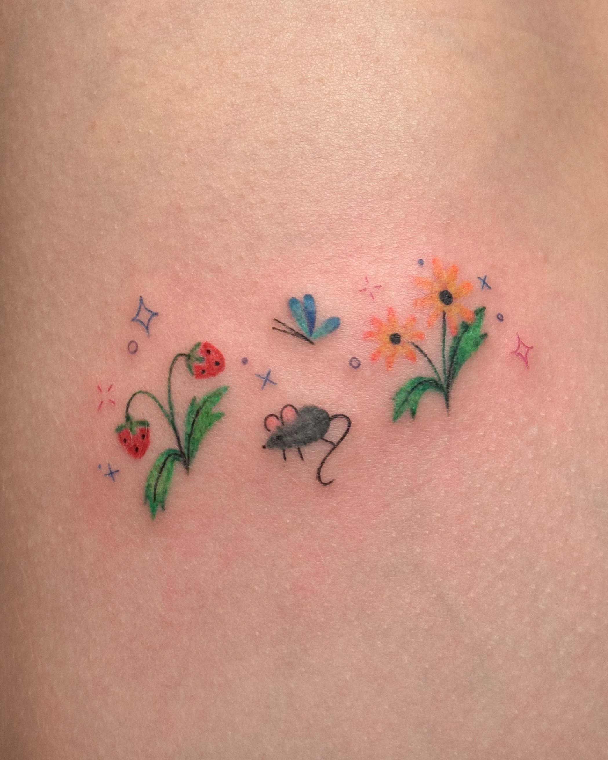 Close-up of a cute tattoo with colorful tattoos of strawberries, flowers, and abstract shapes.