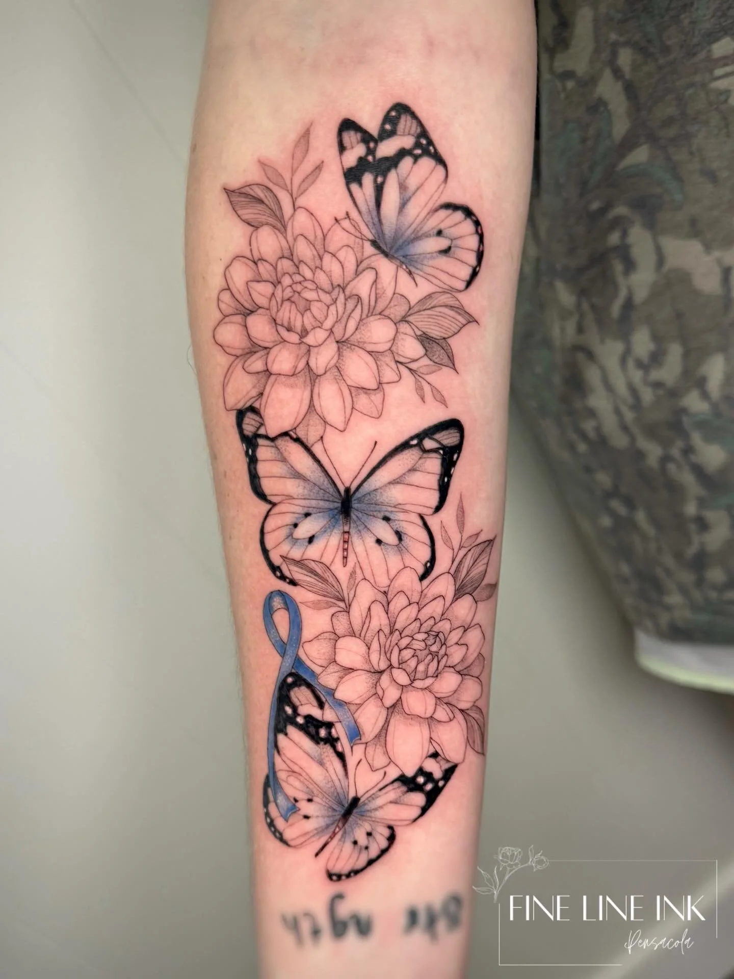 This tattoo is honoring three special women in her life: mom, grandma, &amp; aunt. 

🦋3 butterflies 
🌸Chrysanthemums for her moms birth month 
💙Blue ribbon for grandma beating colon cancer

She gave full creative freedom and it turned out beautifu